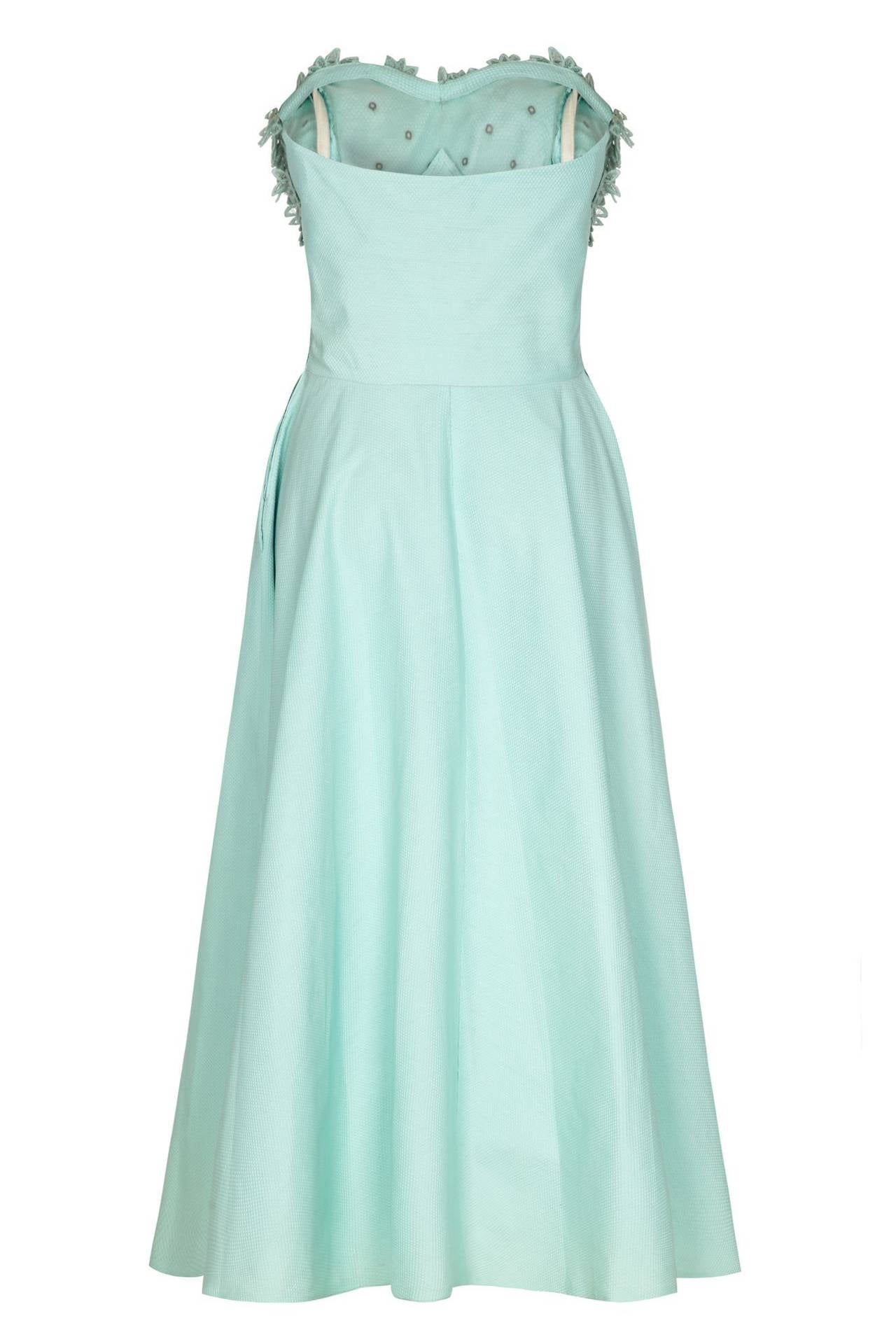This enchanting late 1950s American prom style strapless dress in soft aquamarine textured cotton has a classic feminine aesthetic and is beautifully constructed to showcase an hourglass silhouette. The bodice has a sweetheart neckline and features