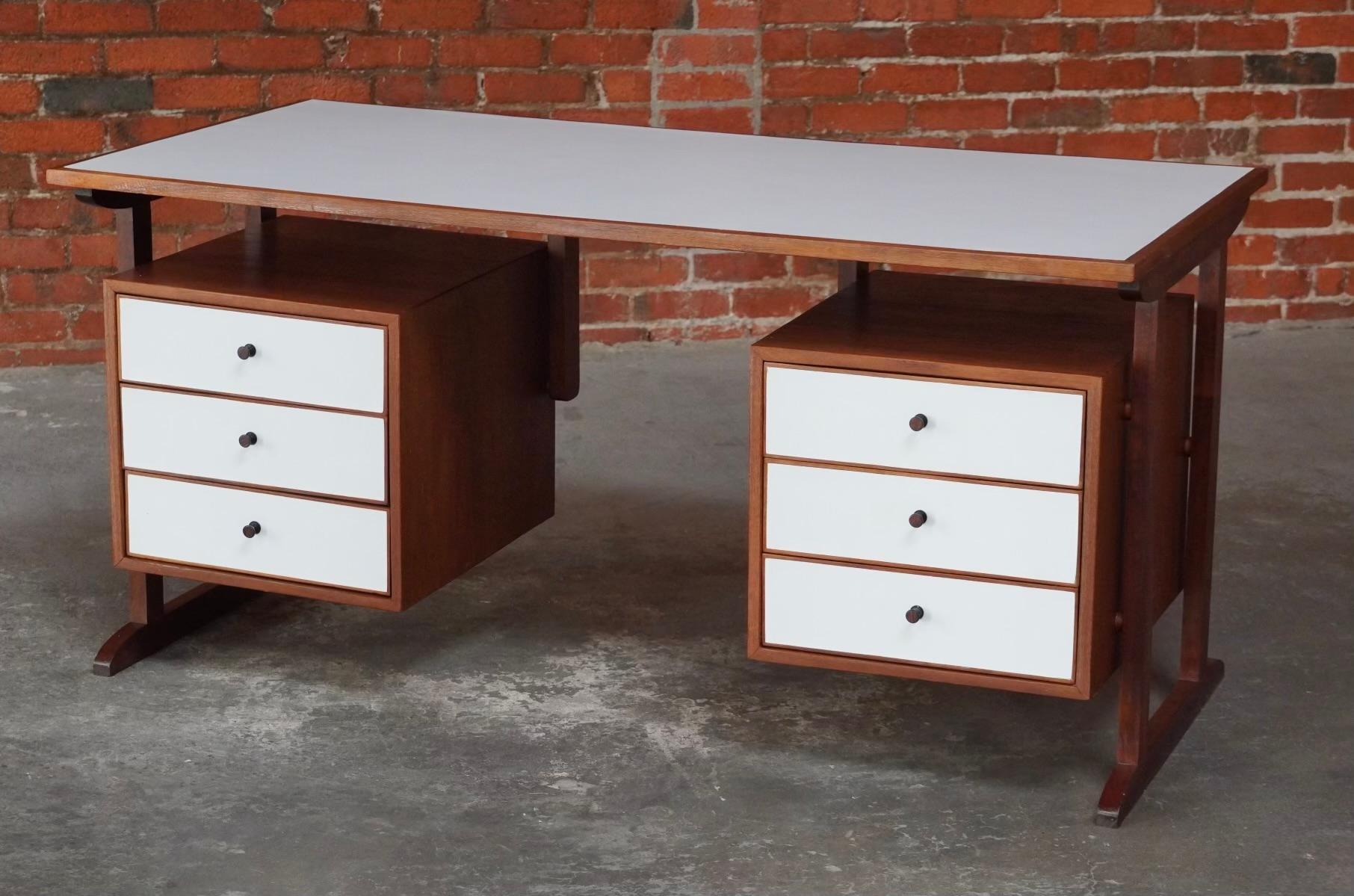 Architect's made and crafted desk created with Philippine Mahogany, white laminate for the top and drawer fronts. Having a double set of three drawers on each side with metal pulls. With a floating top and a double pillar legs in the manner of the