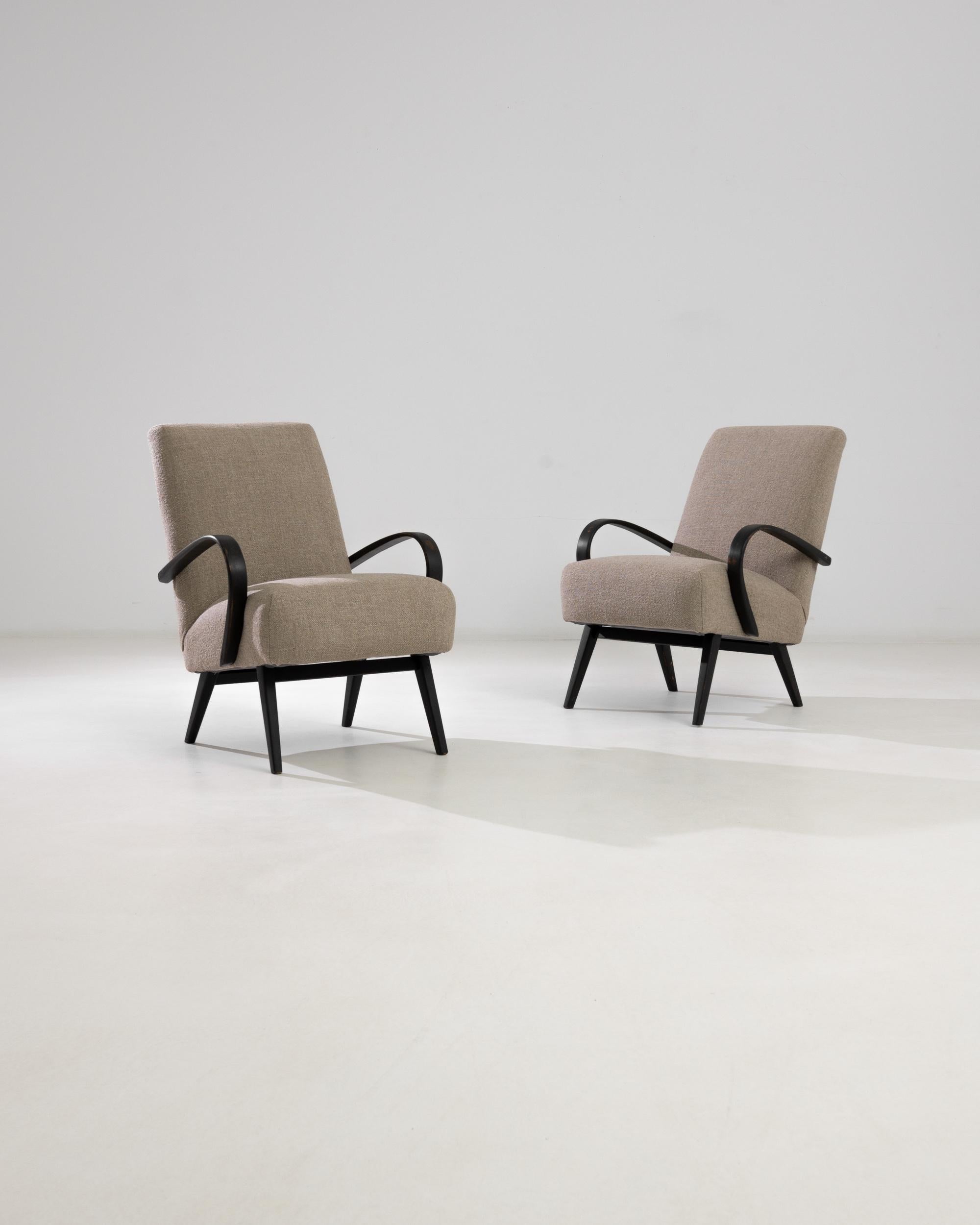 This pair of Mid-Century Modern gems was designed by J. Halabala in Czechia. The iconic frame with bentwood armrests and asymmetrical hay legs punctuate soft geometry of the upholstered backrests and seats. Executed in a rare dark beige tone, they