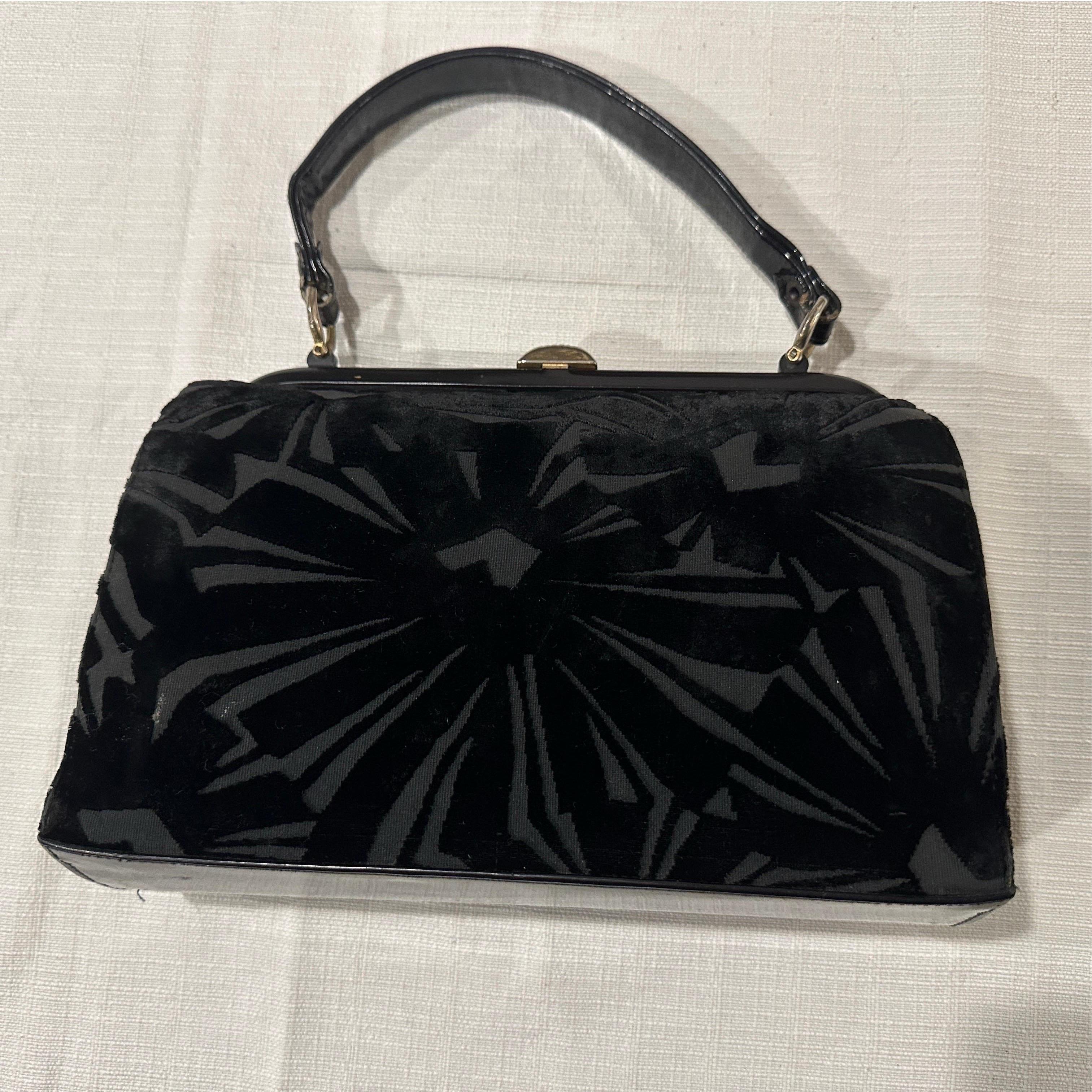 Si tratta di una bellissima borsa vintage con manico superiore, molto stilizzata, probabilmente risalente agli anni '50 o ai primi anni '60.
L'esterno è caratterizzato da un ricco tessuto di velluto nero su un corpo strutturato e incorniciato. Il