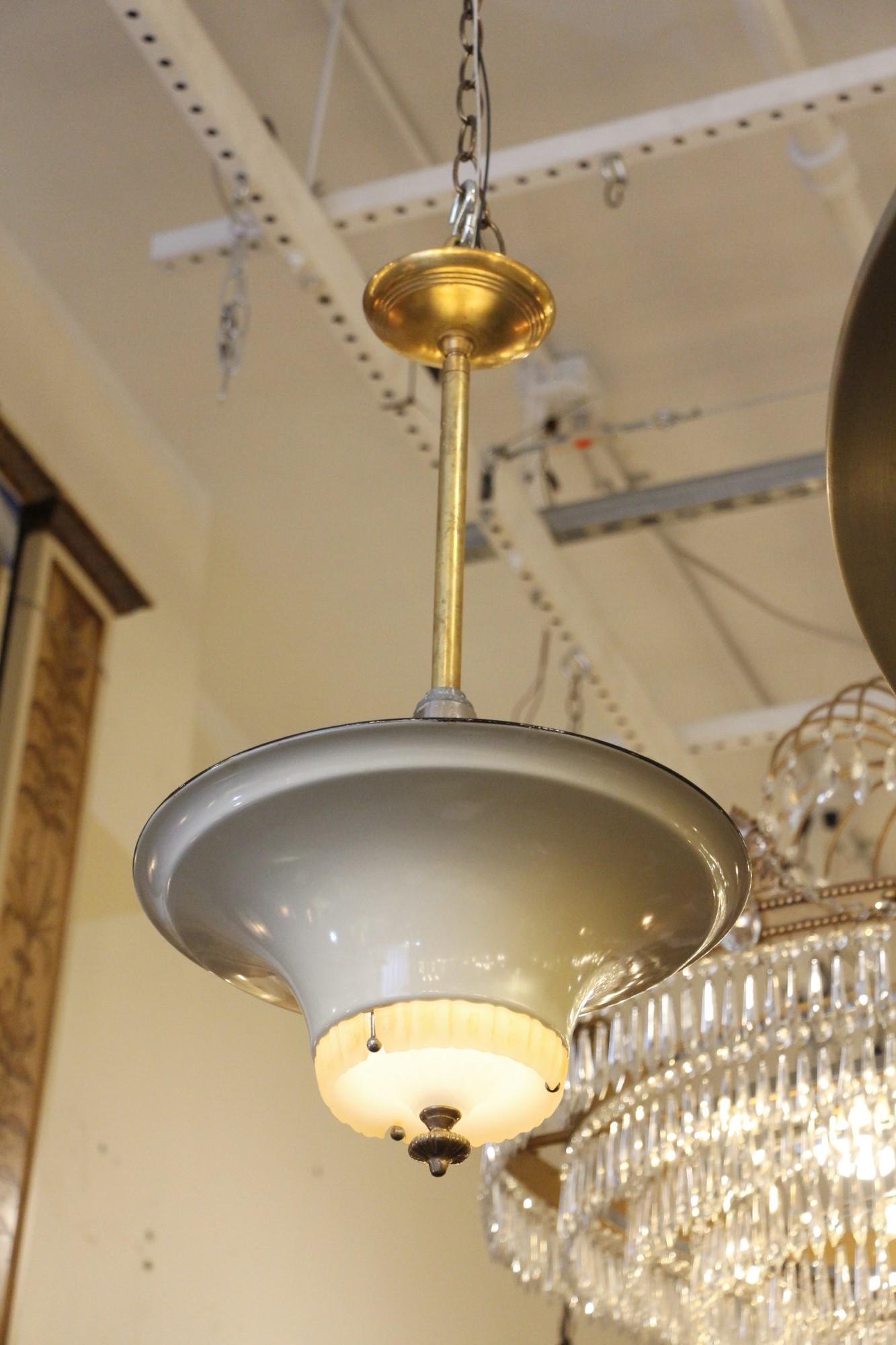 All original Jetson style 1950s enameled metal saucer light with an Art Deco glass center and a clear glass dome above the enamel, which is unseen when hanging. The enamel comes in either gray or cream color. There is also a variation on the finial,