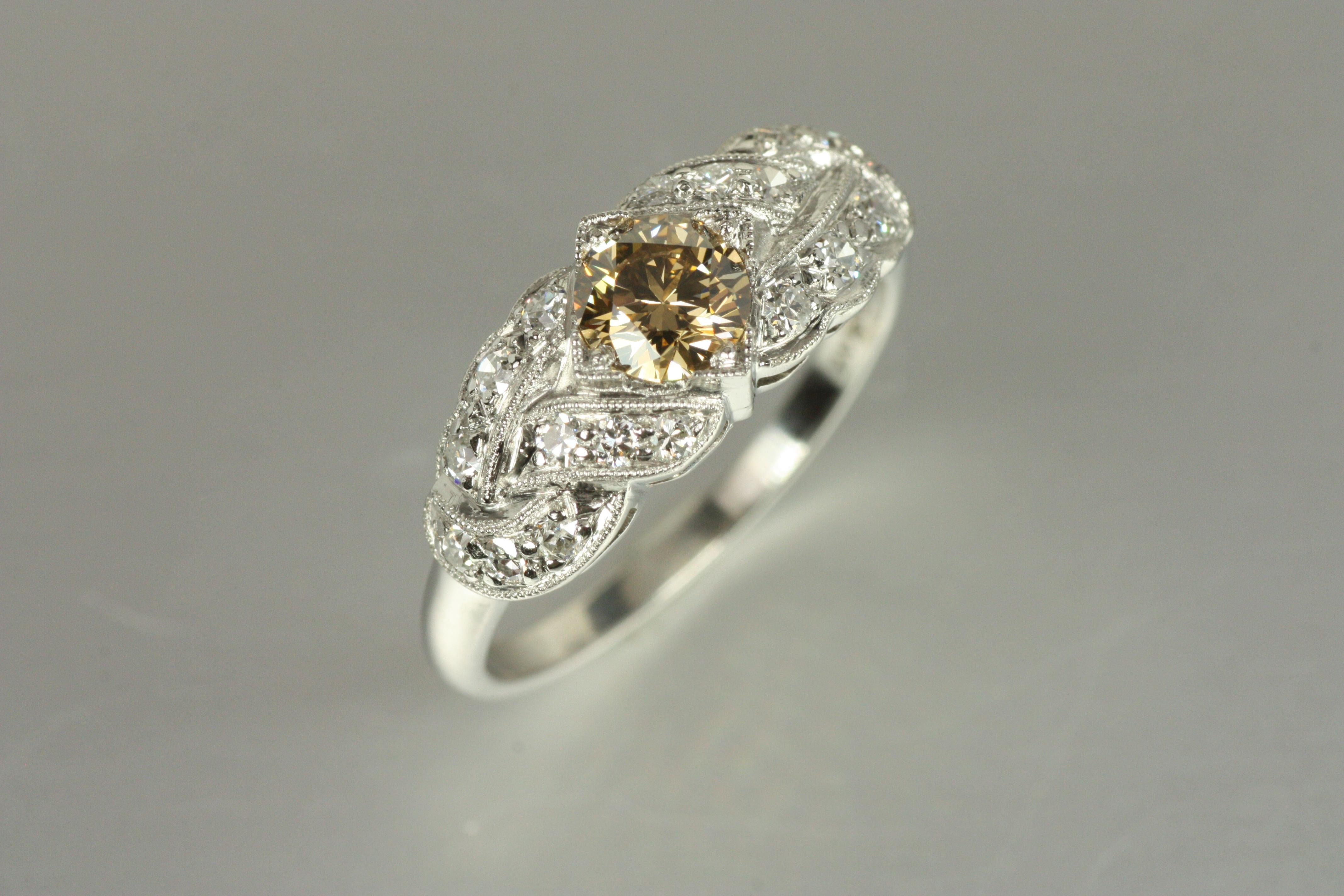An exquisite Art Deco treasure, this 1930s engagement ring captures the beauty of woven design and intricate milgrain detailing. The centerpiece is a 0.49ct brownish yellow natural diamond (VVS2), encircled by 18 white diamonds, creating a