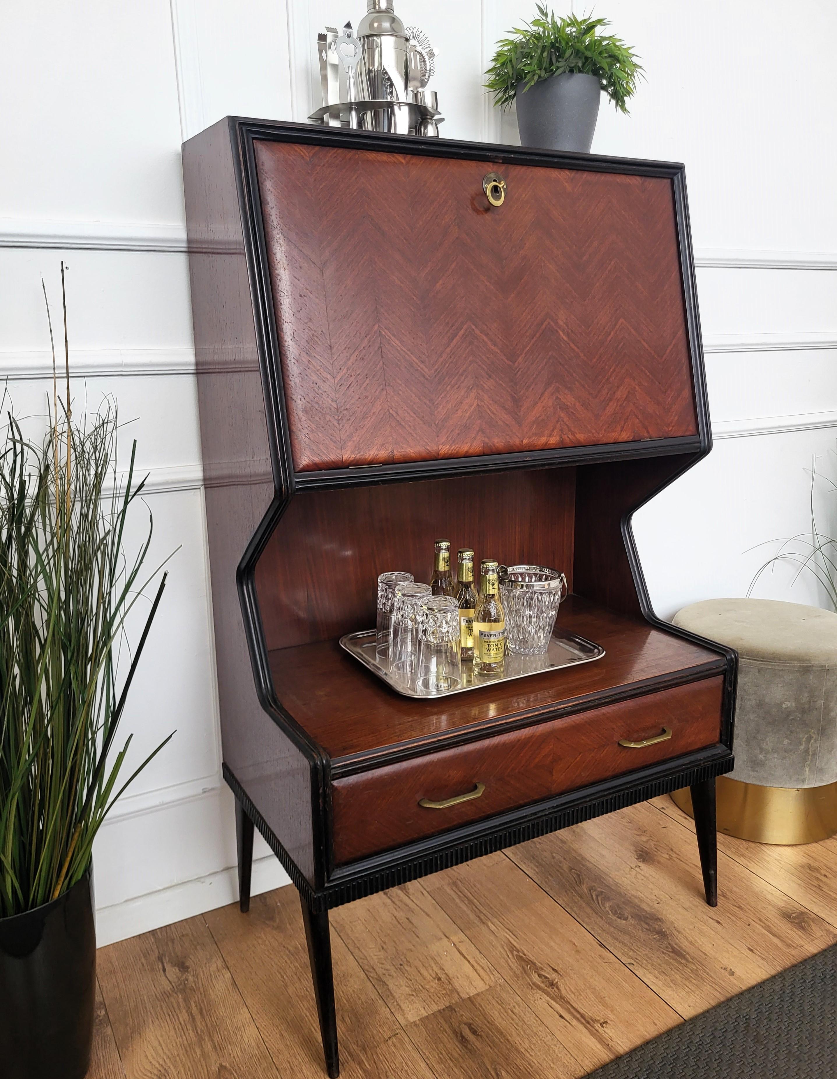 Very elegant Italian Art Deco Mid-Century Modern dry bar cocktail cabinet, in beautiful walnut veneer shaped wood with top part with internal storage and antique brass keylock, a middle shelf and bottom drawer with brass handles. Standing on four