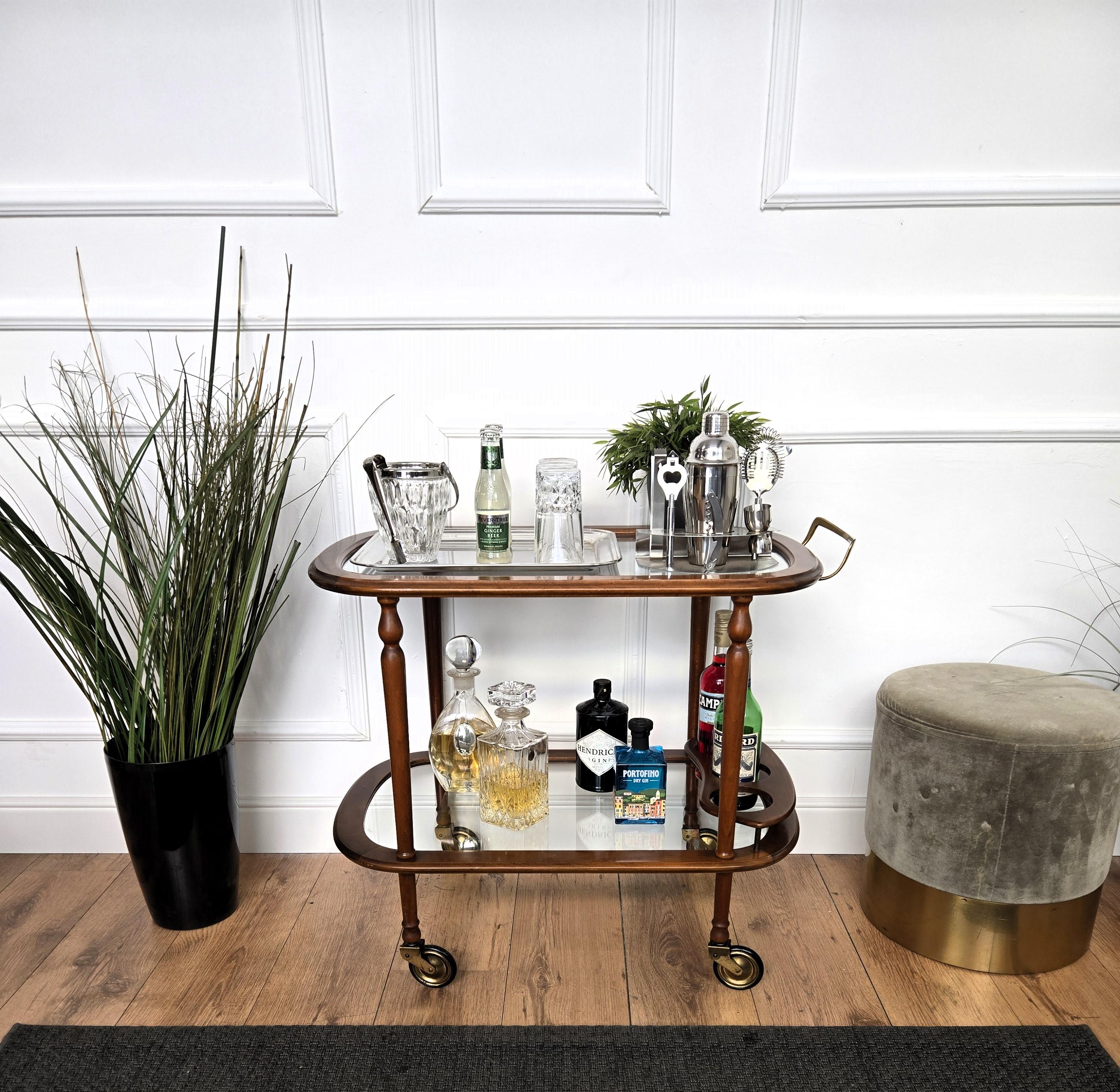 Único y muy elegante mueble bar italiano Art Decó de mediados de siglo, con dos estantes de cristal y realzado por el gran diseño de la estructura de madera y la forma general completada por los detalles del tirador de latón y las ruedas originales