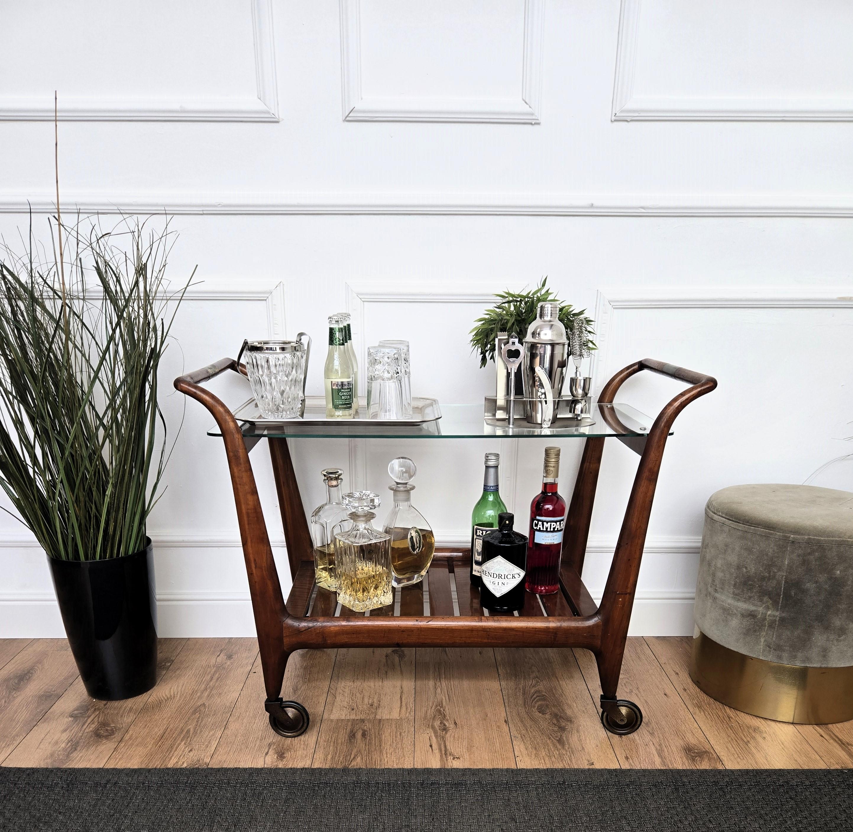 Unique et très élégant chariot de bar à sec Art Deco italien avec un étage supérieur en verre, mis en valeur par le design de la structure en bois et la forme générale complétée par les détails des poignées en laiton et les roues en laiton antique