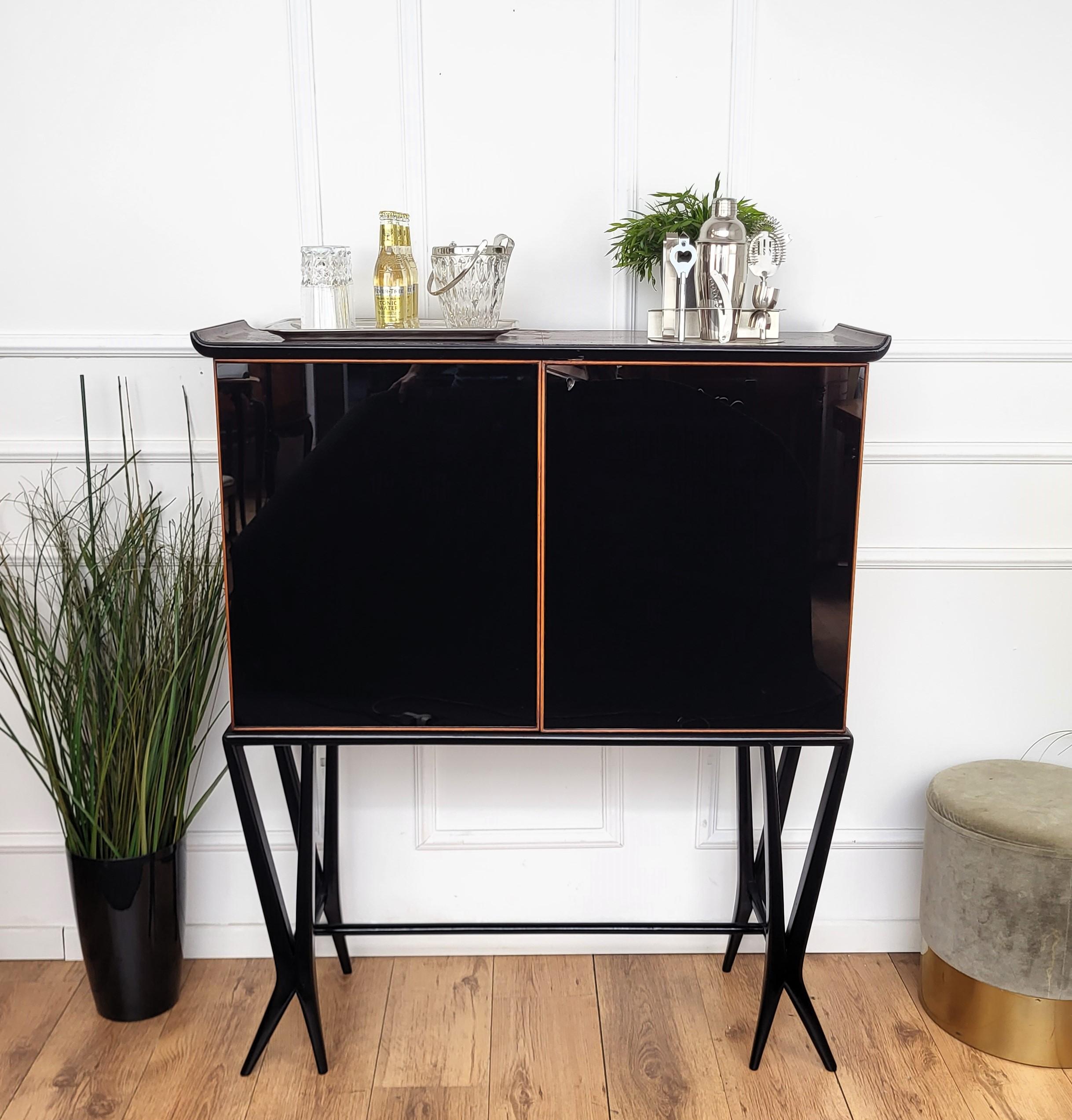 Impressionante credenza bar italiana degli anni '50 con ante frontali in vetro nero splendidamente eseguite, con piano tipicamente a forma di onda e sostenuto da otto gambe intagliate. Una volta aperte le due porte con ripiani laterali in vetro,