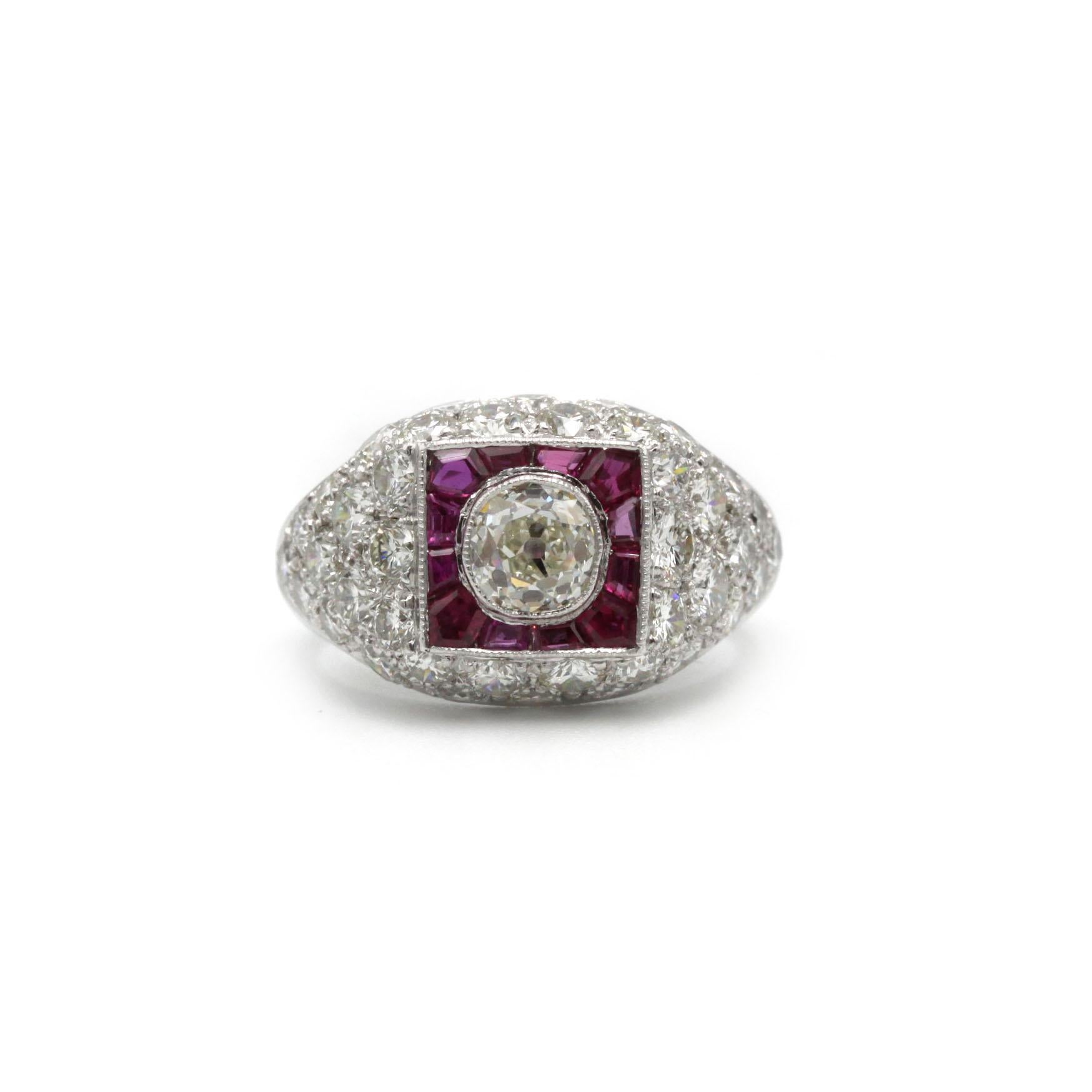 Une bague d'inspiration Art of Vintage des années 1950, réalisée en platine massif, où la géométrie vintage rencontre l'éclat lumineux. En son cœur se trouve un diamant taille ancienne (estimé à ~0,60 carat) serti dans un cadre carré de rubis