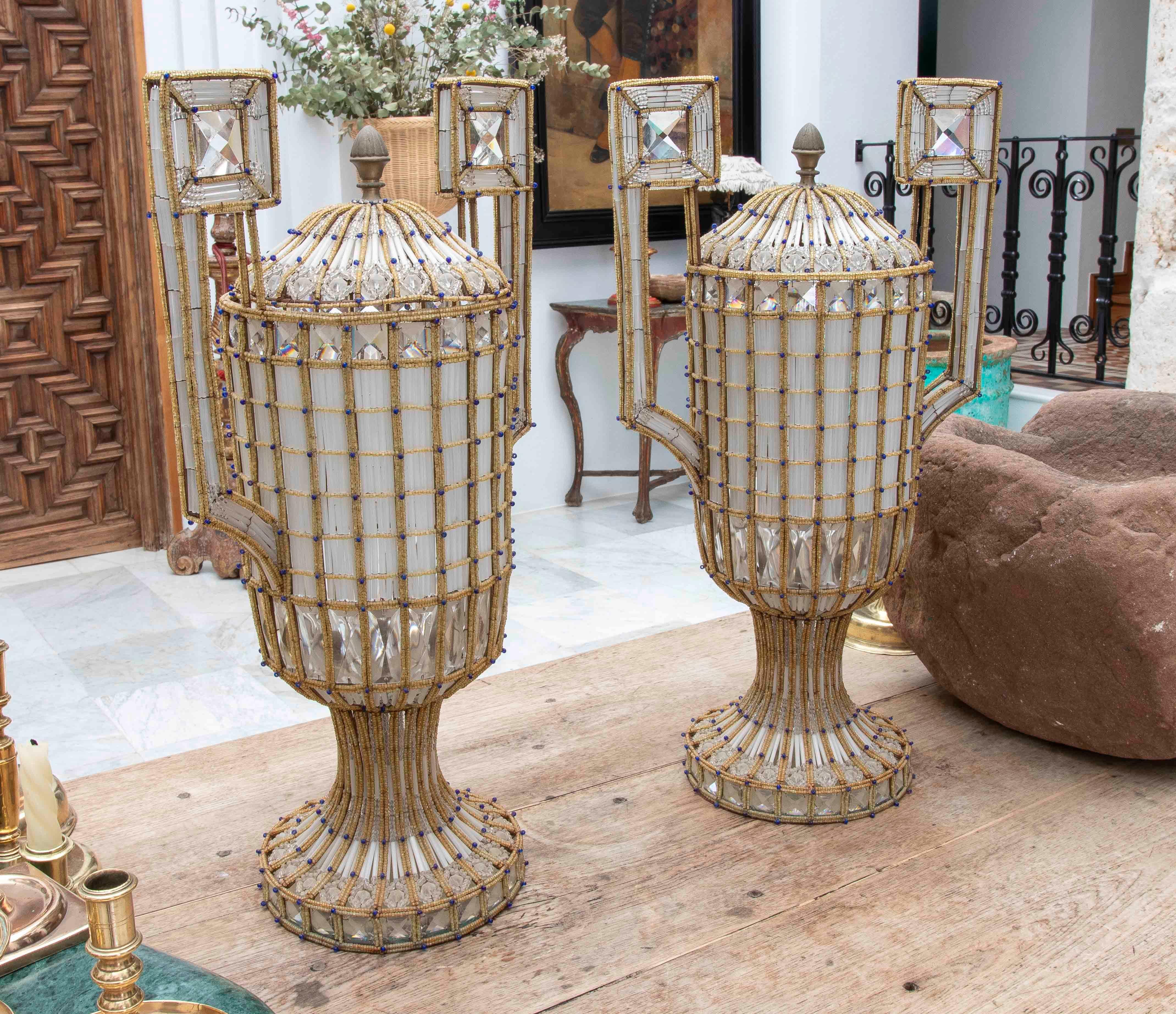 Une paire spectaculaire de lampes décoratives de grand format, conçues en forme d'urne classique d'inspiration Empire, fabriquées à partir d'une structure en métal renforcé avec une finition or antique et richement recouvertes d'un filet de perles