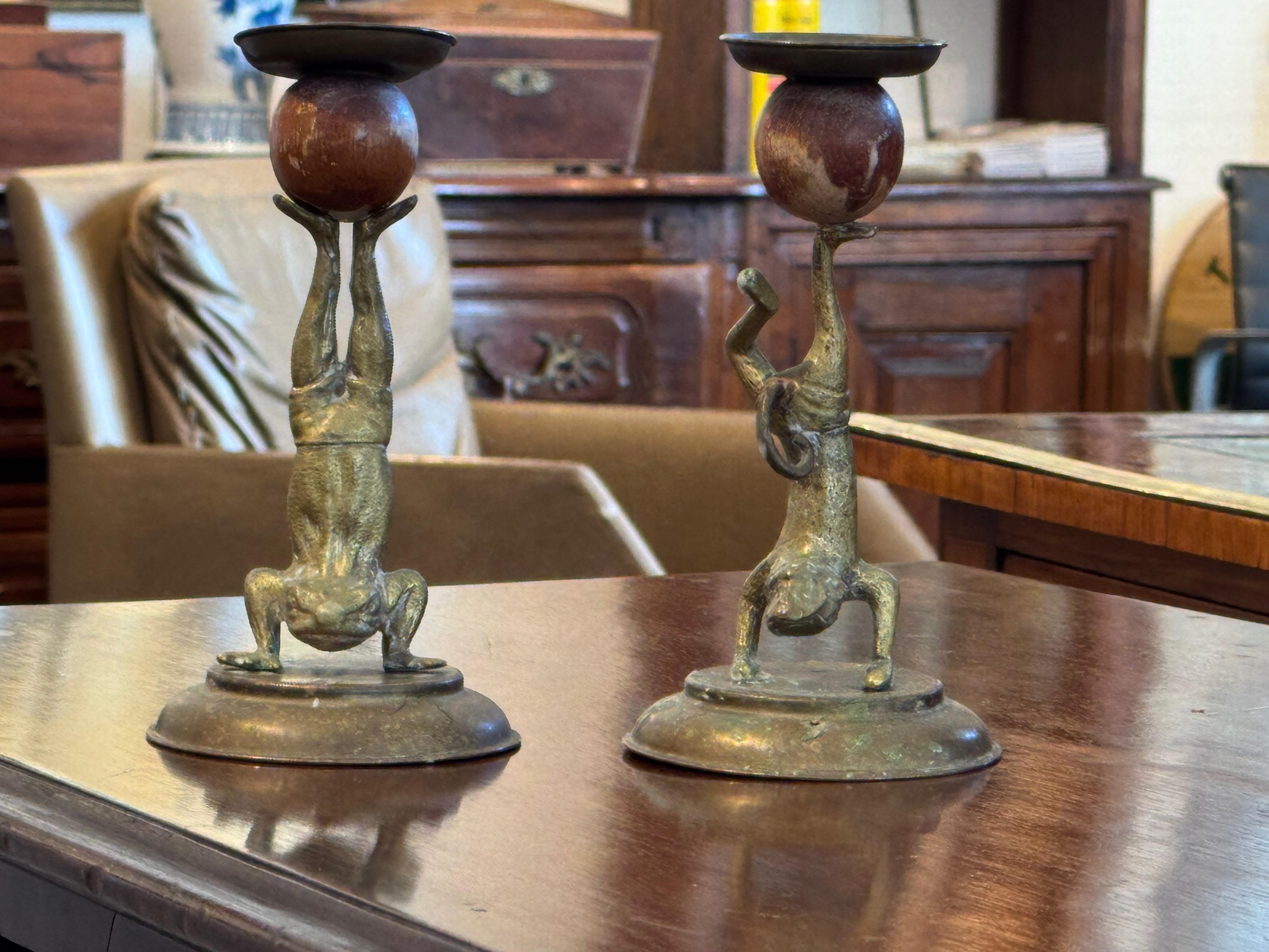 Stravagante coppia di candelieri Arthur Court con rane in ottone fuso in pose giocose e capovolte, ognuna delle quali tiene in equilibrio un portacandele. La patina invecchiata aggiunge carattere ai dettagli scultorei, mentre il mix di elementi in