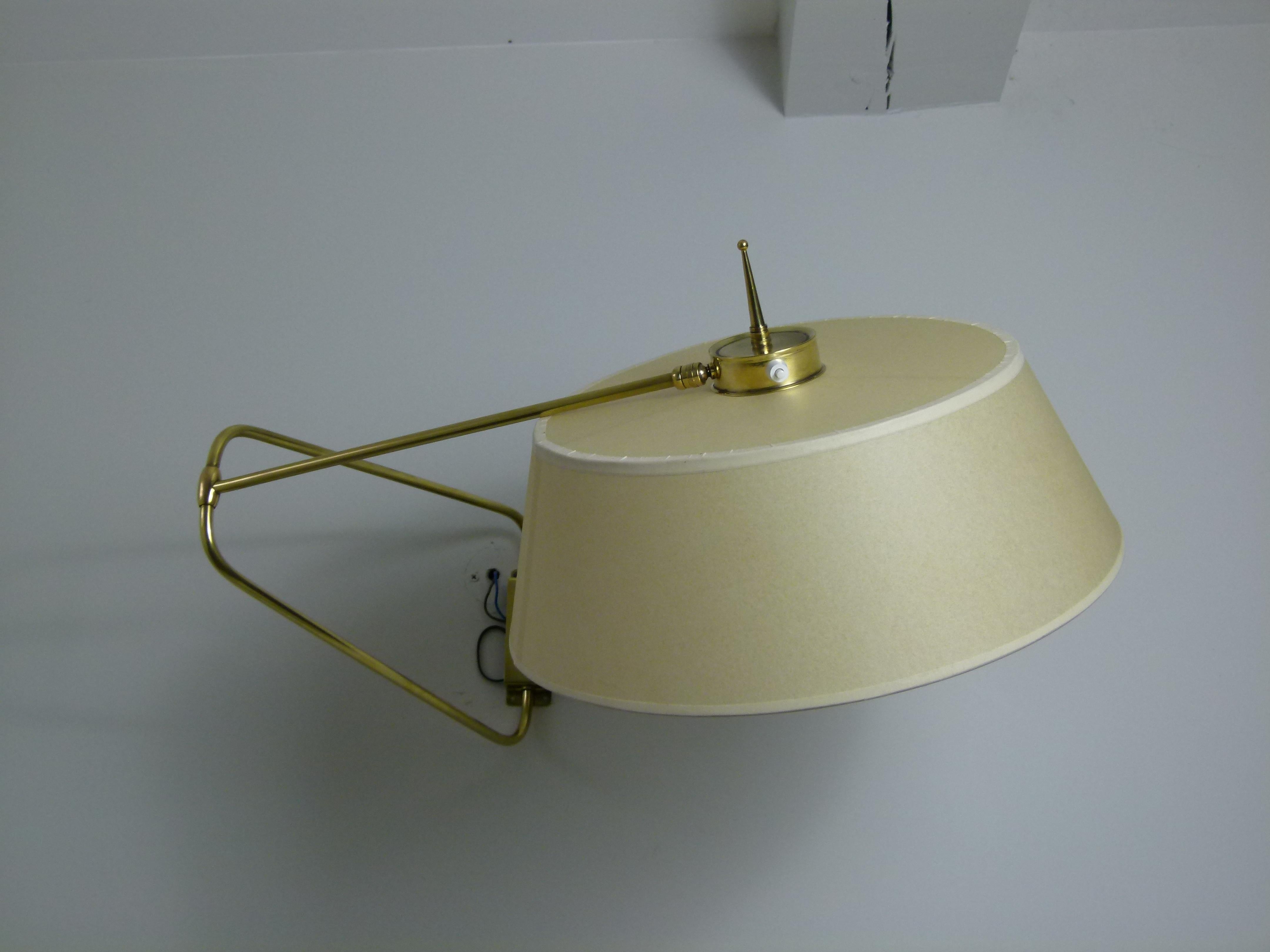 Brass wall lamp composed of a rectangular brass base on which is placed a double swivel rod linked to an articulated brass arm.
A lampshade placed at the end of the arm, connected by a ball joint which allows the orientation of the light.
A small