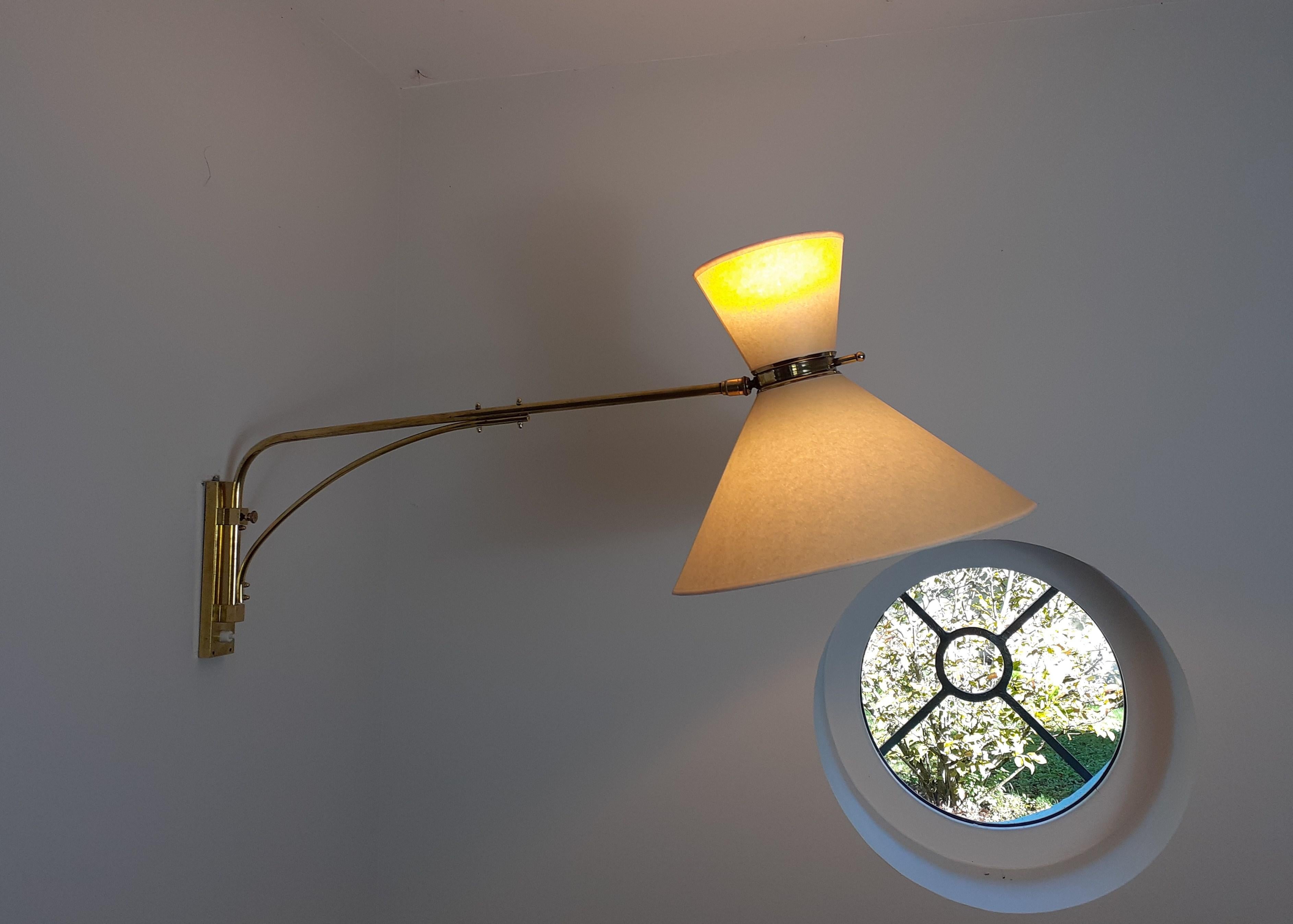 Brass wall lamp composed of a rectangular brass base on which is placed a swivel rod from right to left linked to an articulated brass arm.
Two conical shades placed at the end of the arm, connected by a ball joint which allows the orientation of