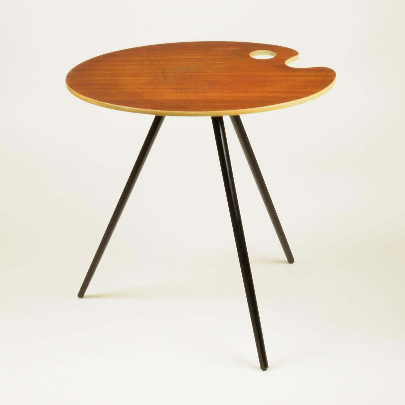 Une charmante petite table basse ou d'appoint à palette d'artiste des années 1950.
Elle est dans le style de Lucien De Roeck (voir ses dessins pour une table similaire fabriquée par Bois Manu, pour l'Expo 1958 de Bruxelles).
Elégant, délicat,