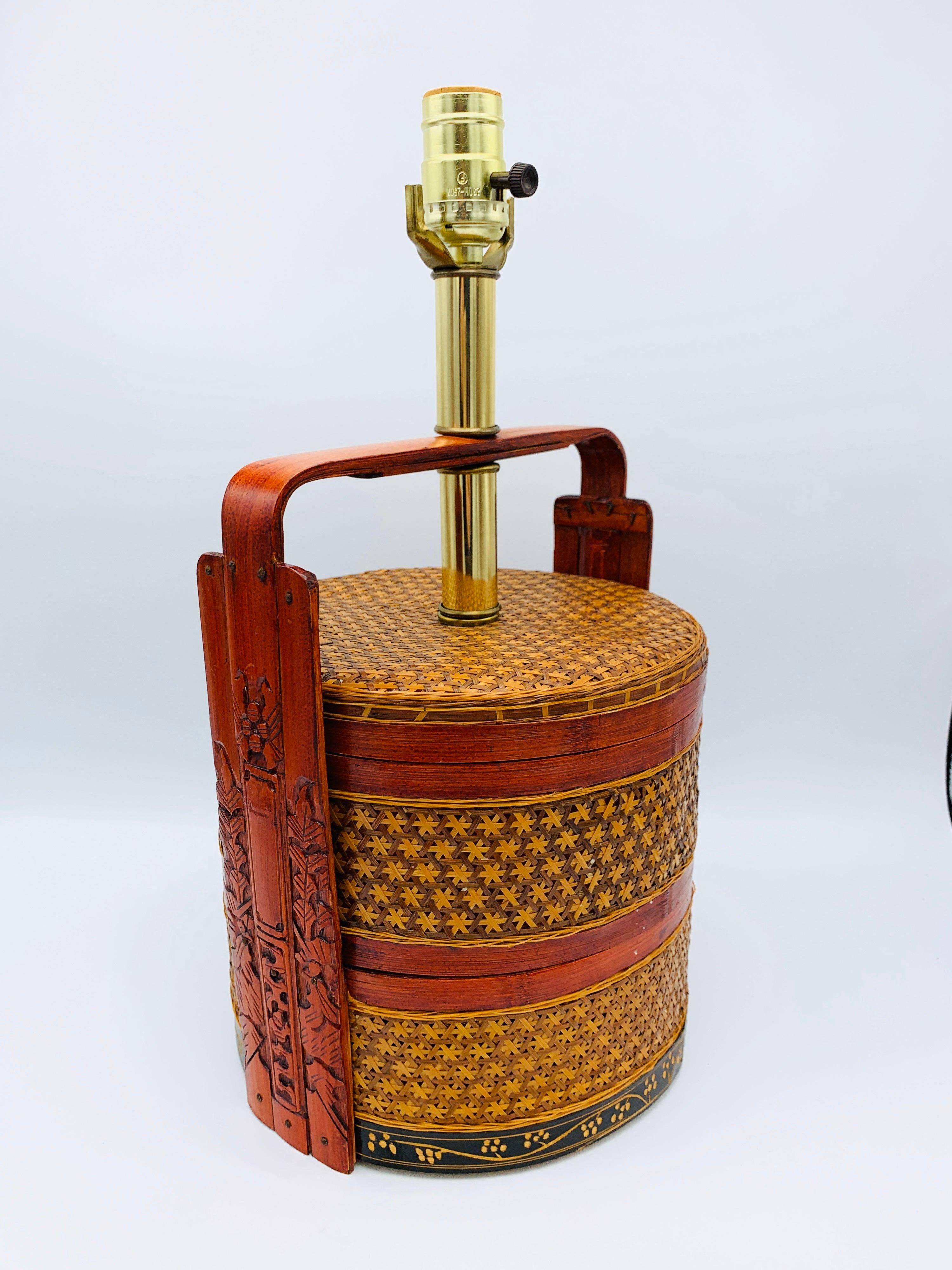 Listed is a gorgeous, 1950s Asian grain basket lamp. The lamps body is a woven rattan grain basket, with red lacquered detailing and a hand painted black and floral lower collar. Brass neck and socket. Heavy, 2.4lbs.