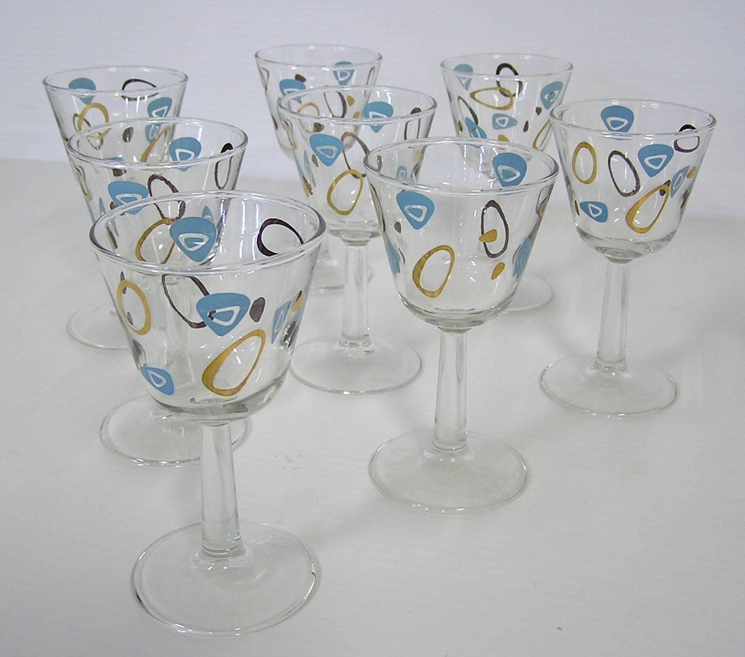 A set of eight retro wine glasses from the 1950s Mid-Century Modern era. Manufactured by the federal glass company and commonly referred to as amoeba boomerang glasses this set is wonderfully decorated throughout in a turquoise and 22-karat gold