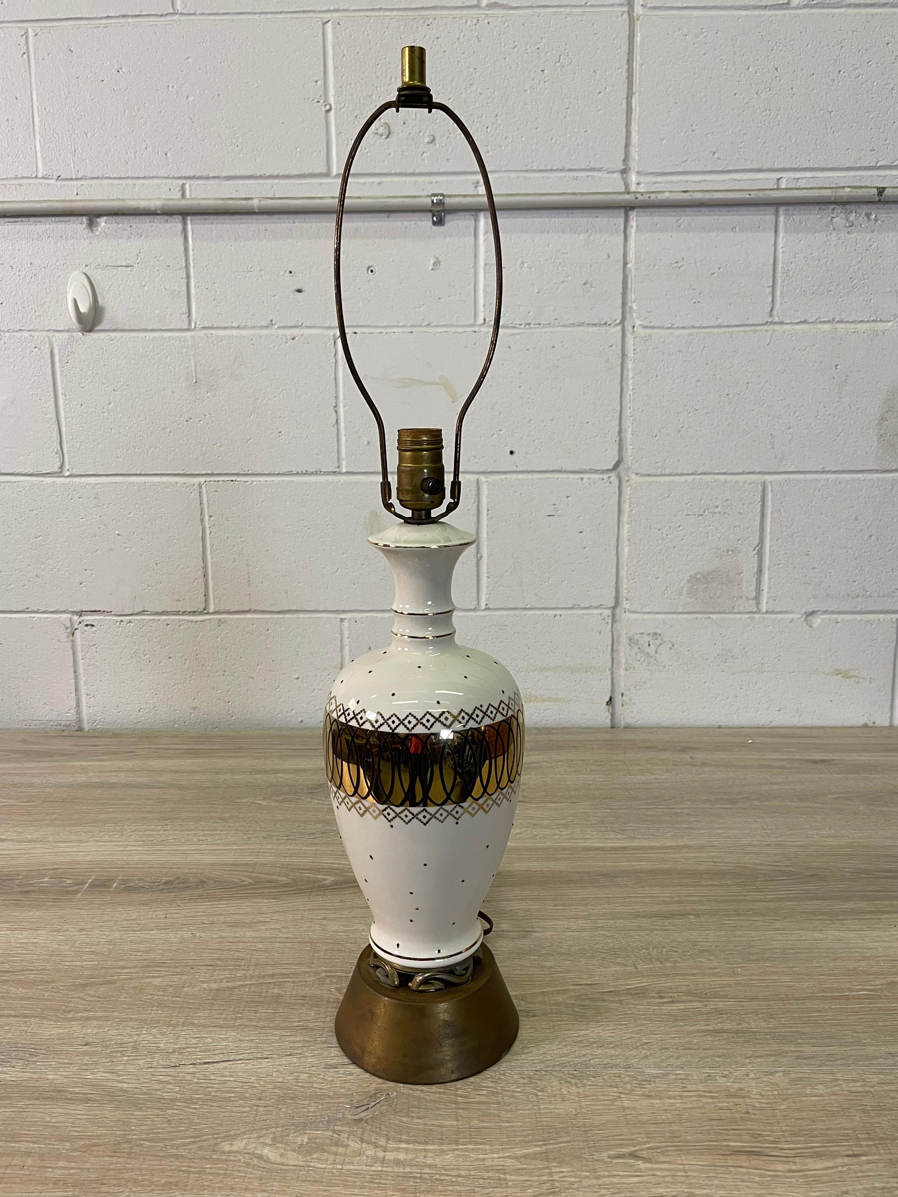 Vintage 1950s atomic style table lamp. The lamp is a cream colored ceramic with an atomic black design. There are also black dots on the lamp to accent the design. The lamp has a floral brass base. Wired for the US and in working condition. Harp, 