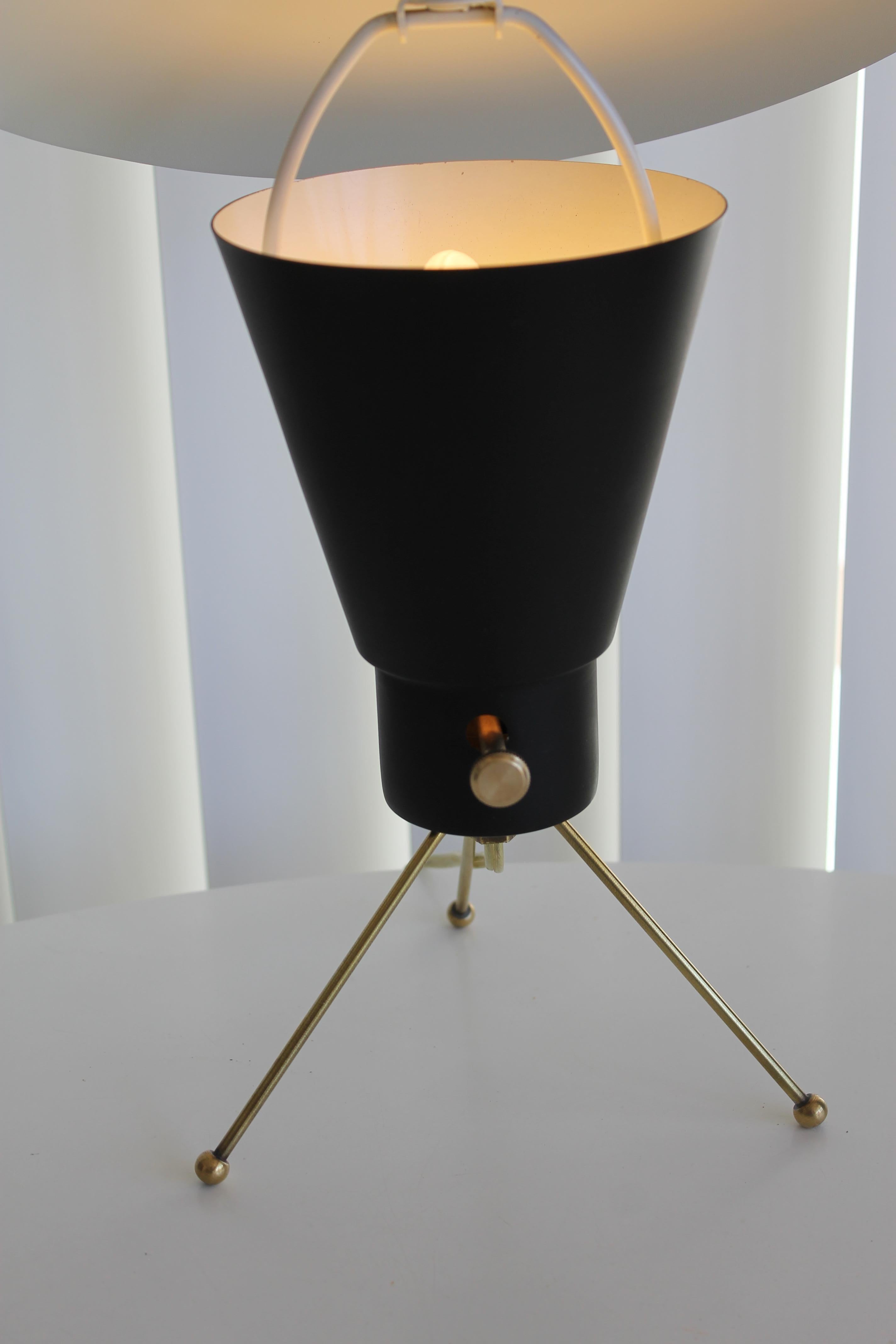 A small midcentury lamp with swiveling saucer light deflector. Tripod base is solid brass. The lamp stands 14