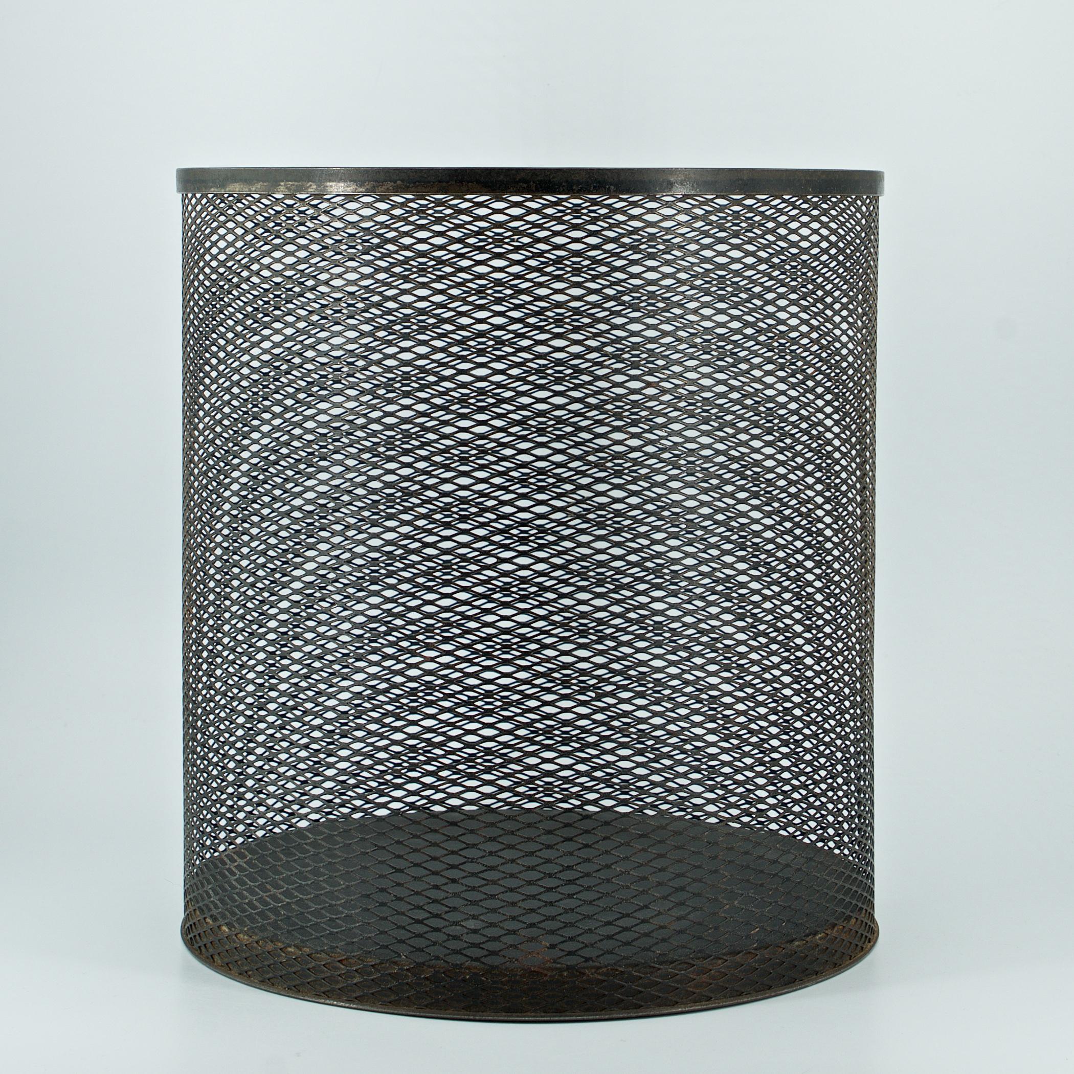 Finely expanded metal sheet rolled wastebasket with reinforced lip and bottom tray. 

This type of metal deformation was invented in England in 1884 by John French Golding. This type of process lightens the metal, and because the steel is