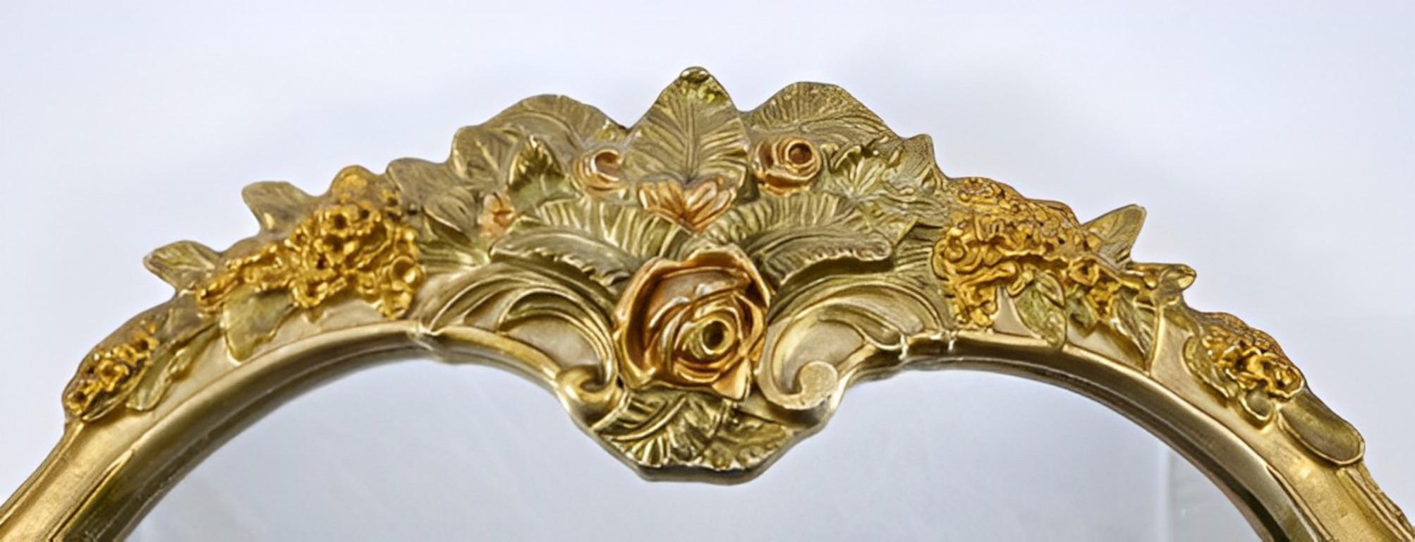 Miroir de table original et lourd d'Atsonea, présentant un décor de style rococo dans des tons d'or avec des fleurs, des feuilles et des guirlandes. Il est doté d'un support texturé. Il y a un bras d'appui décoratif pliant. Ce magnifique miroir est