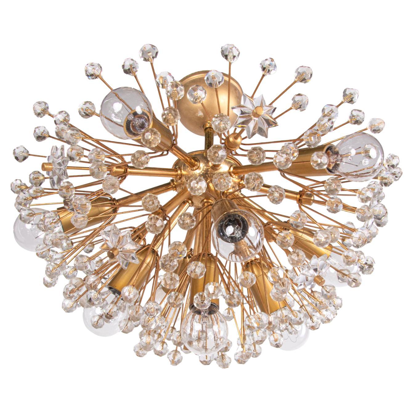 Elegant semi flush mount sputnik snowball chandelier with crystal flowers on a brass frame designed by Emil Stejnar for Rupert Nikoll, Vienna, Austria in the 1950s. 
This beautiful polished brass chandeliersupports clusters of dandelions that are