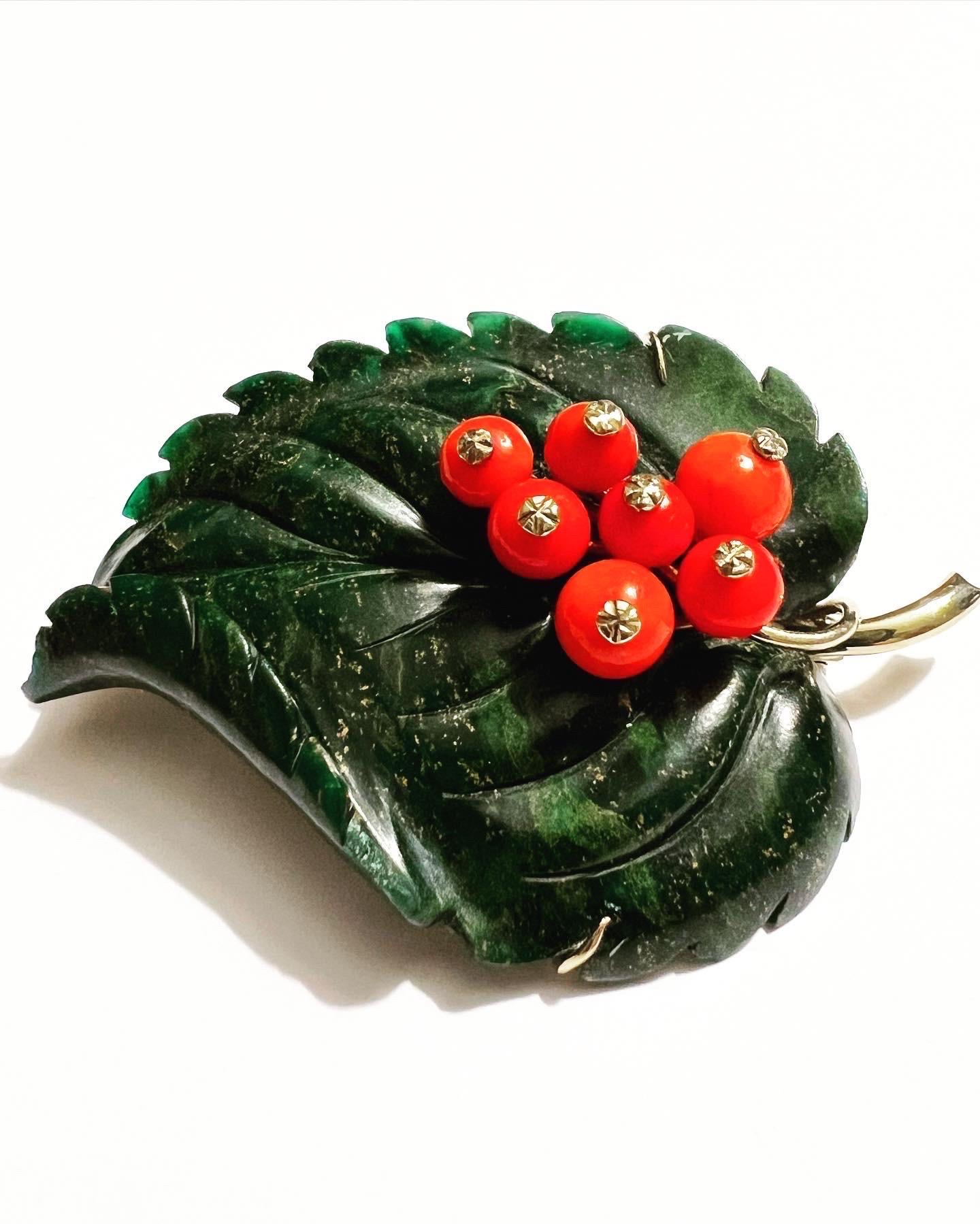 Made in Vienna, Austria in the 1950s.  
The brooch is finely modeled as a beautiful leaf.
The green leaf is naturalistically carved from a single piece of nephrite jade and as fruits there are coral spheres.
The structure is made of 14K gold. 