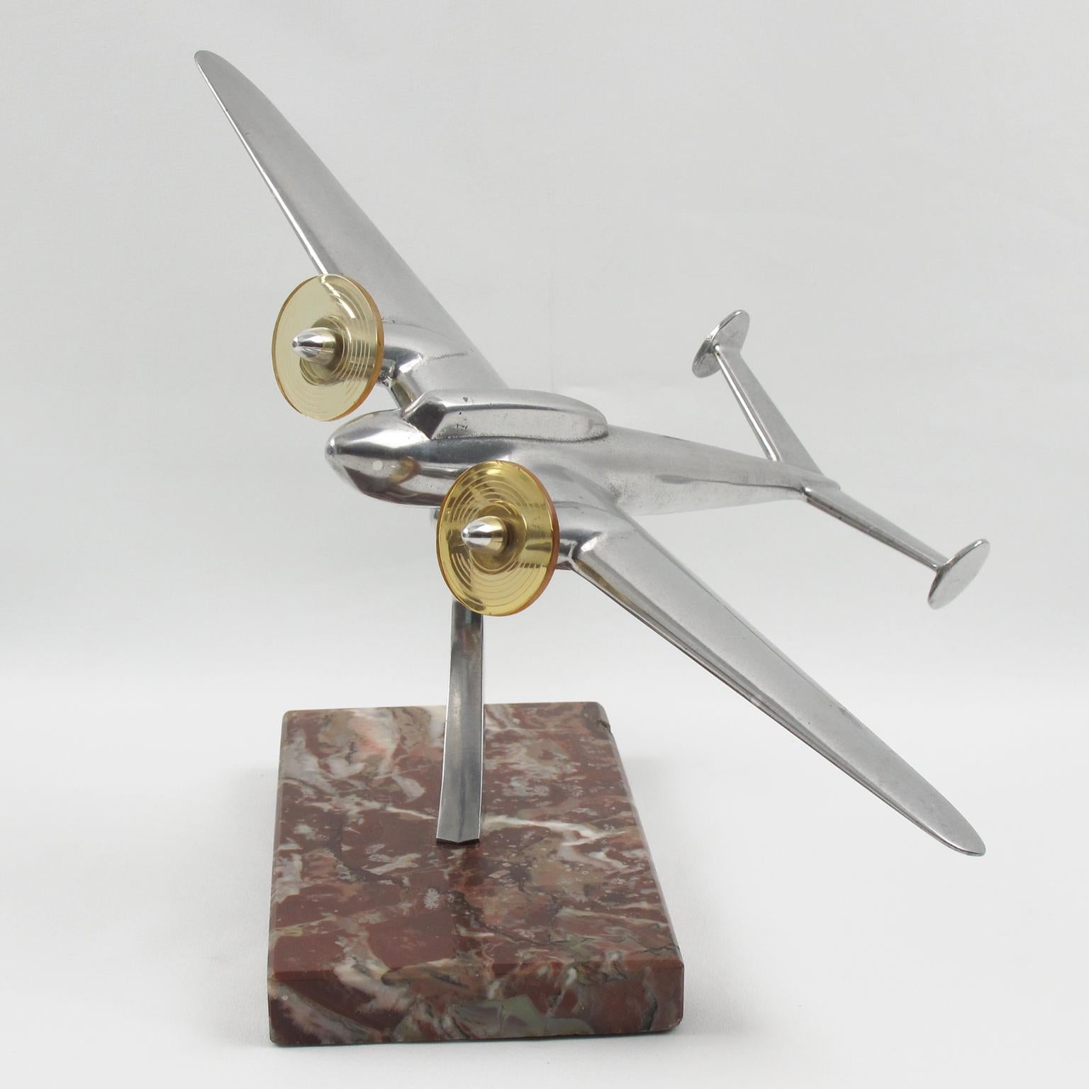 Elegant French aluminum airplane model, mounted on a marble plinth. This nice sculptural model airplane is made with cast aluminum and has two original Lucite propellers. Standing on a geometric marble plinth in warm red/brown swirl color with
