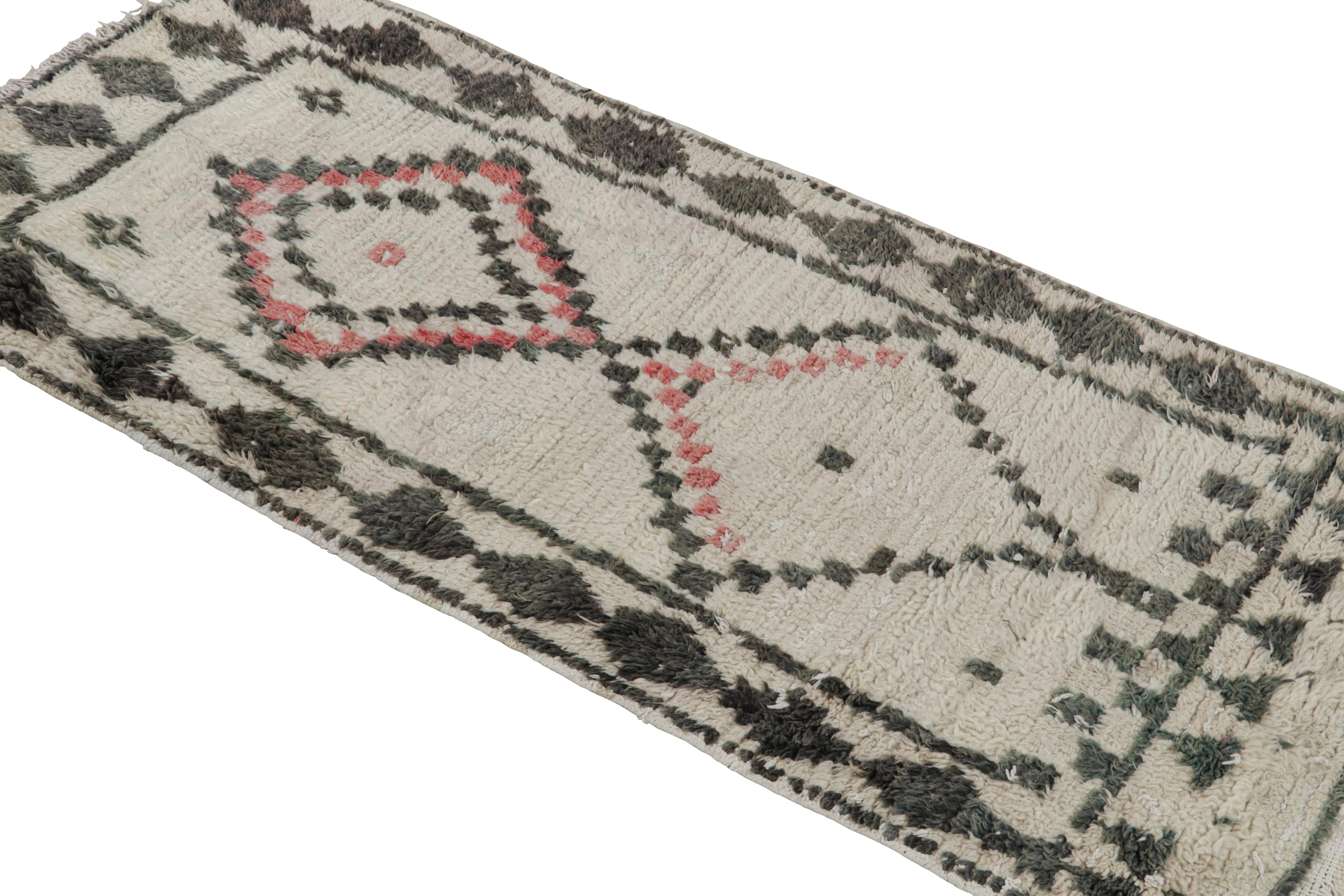 Hand-knotted in wool circa 1950-1960, this vintage 2x6 Moroccan rug is believed to hail from the Azilal tribe. 

On the Design: 

This rug enjoys red and black diamond patterns on a white background. Keen eyes will further admire its healthy