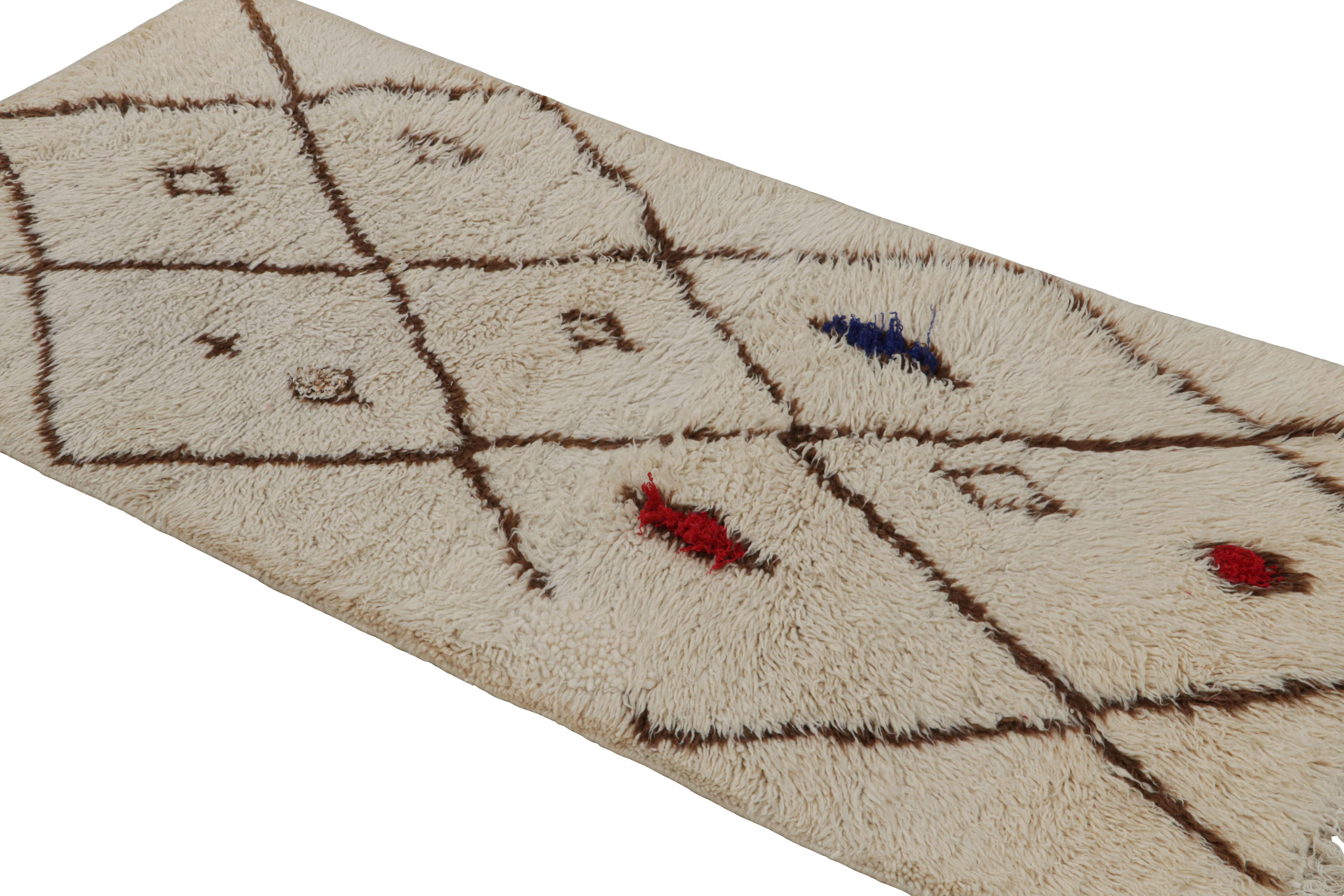 Hand-knotted in wool circa 1950-1960, this vintage 3x6 Moroccan runner is believed to hail from the Azilal tribe. 

On the Design: 

This runner enjoys beige-brown diamond patterns with red and blue punctuations. Keen eyes will further admire its