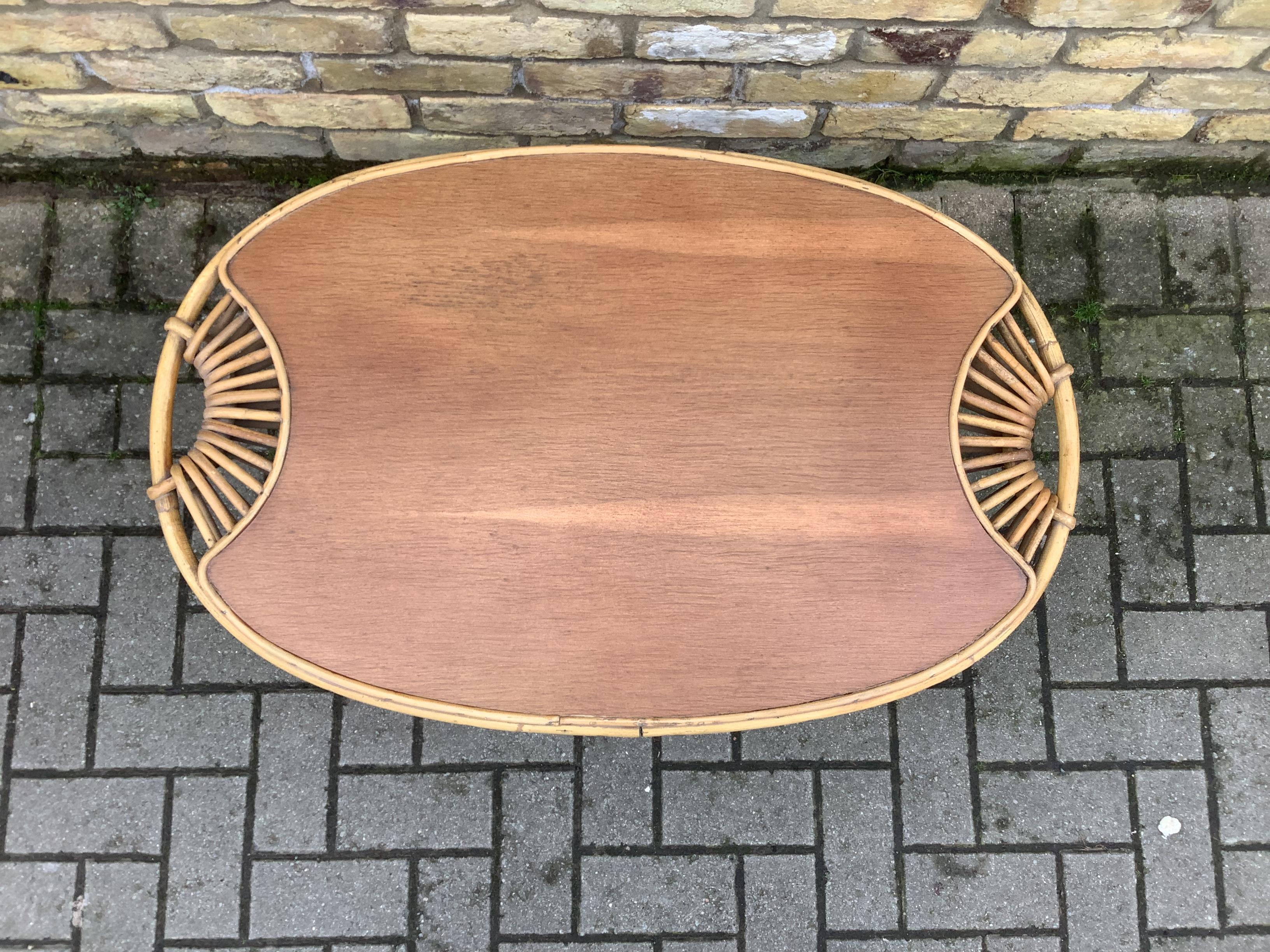 Janine Abraham (1929-2005) Lemon table, circa 1950. Rattan table of lemon shape, with magazine rack under the top. Handles worked in wicker. Very good condition. Nice honey colored patina. Some traces of wear (notably scratches on the tray) H 50cm,