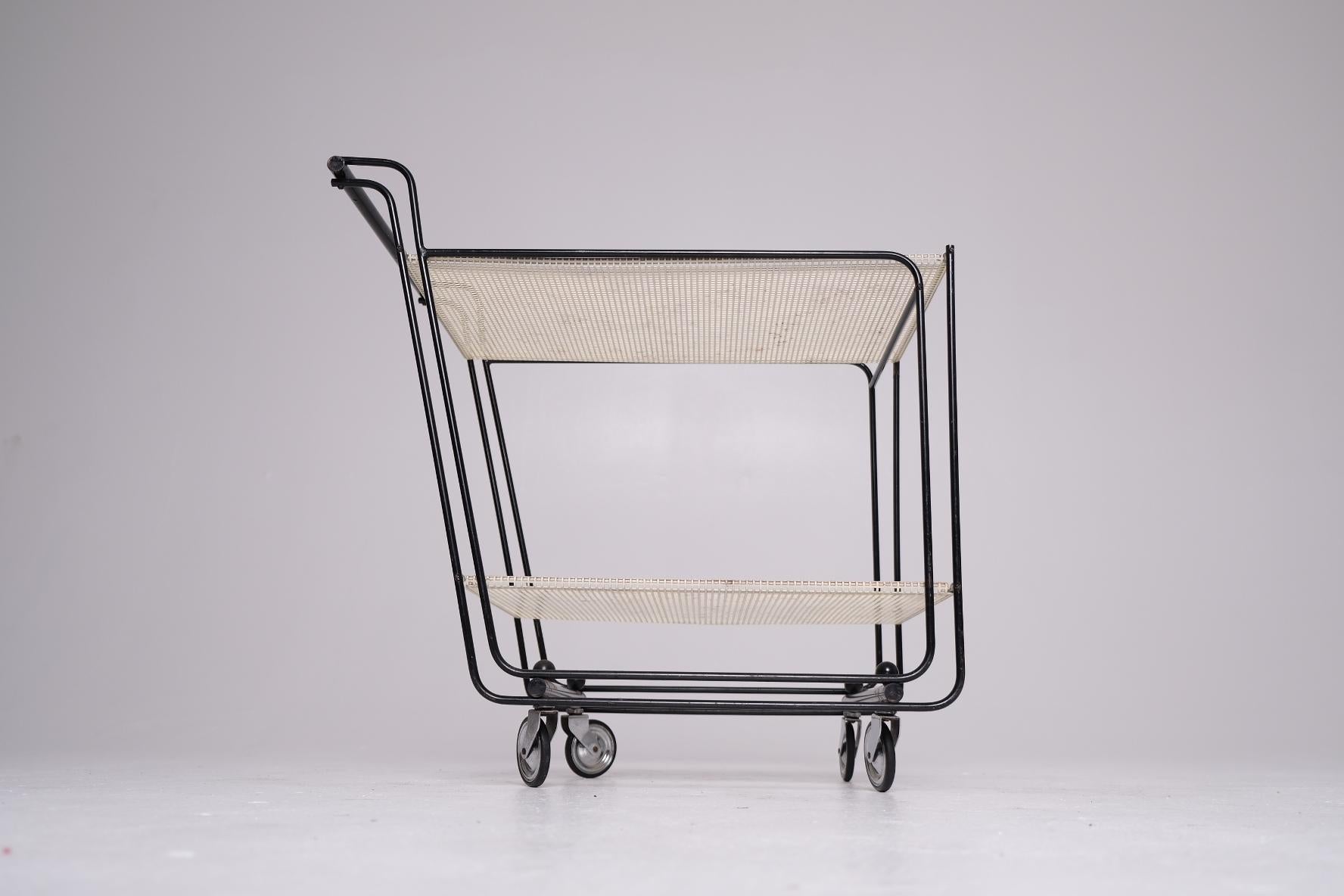 An exceptionally rare and architecturally refined mid-century bar cart, dating to the 1950s and constructed with a tubular steel frame and two tiers of wrapped perforated steel shelves. The use of rolled-edge perforated metal — rather than flat mesh