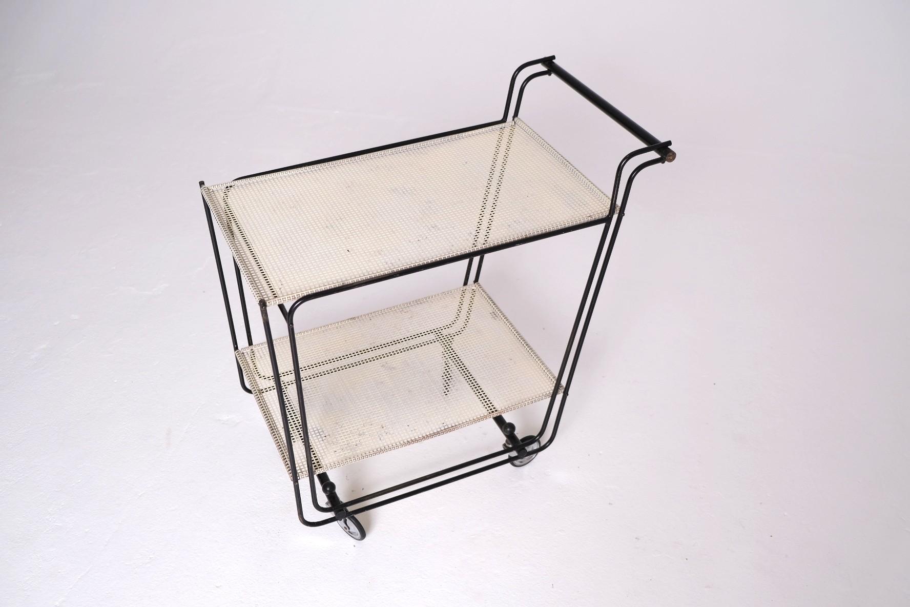 An exceptionally rare and architecturally refined mid-century bar cart, dating to the 1950s and constructed with a tubular steel frame and two tiers of wrapped perforated steel shelves. The use of rolled-edge perforated metal — rather than flat mesh