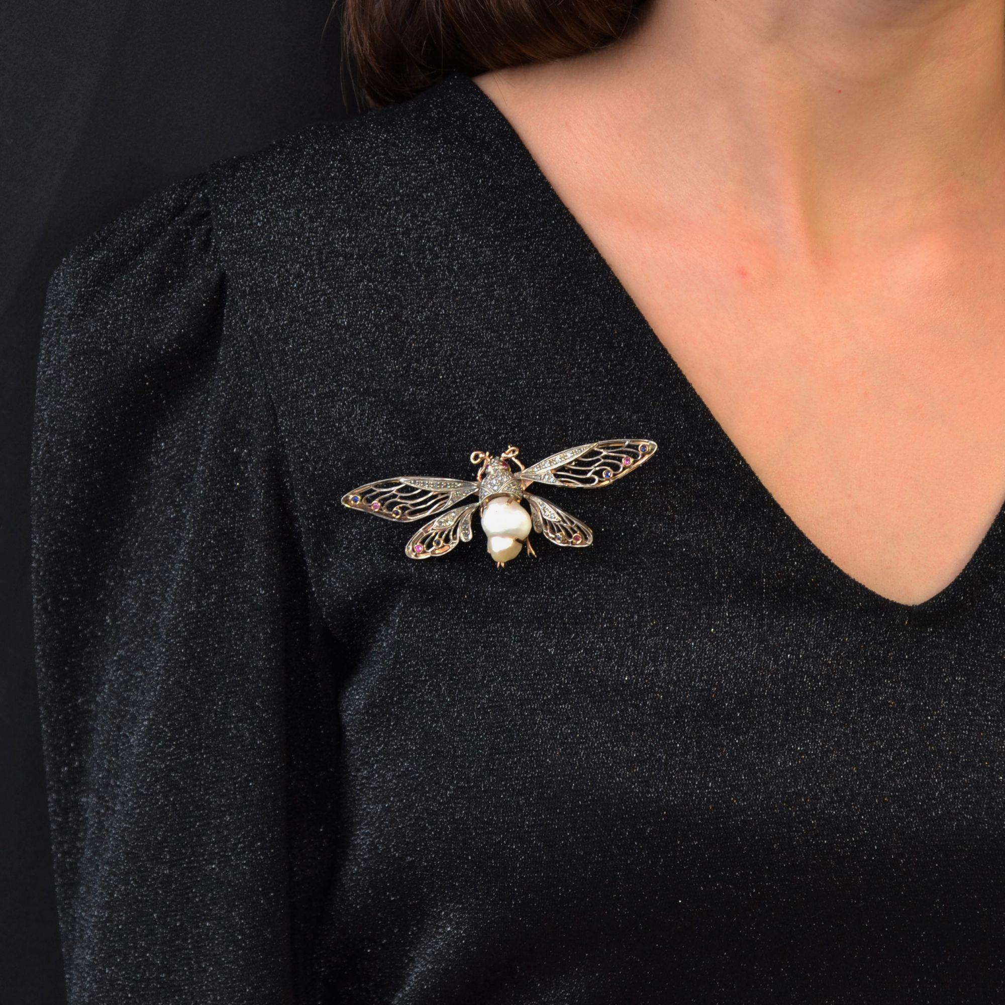 Brooch in 14 karat yellow gold, shell hallmark.
Important brooch in the shape of an insect, the bottom of the body is represented by a baroque pearl, the top and the head are paved with rose-cut diamonds. The eyes are rubies, the four openwork wings