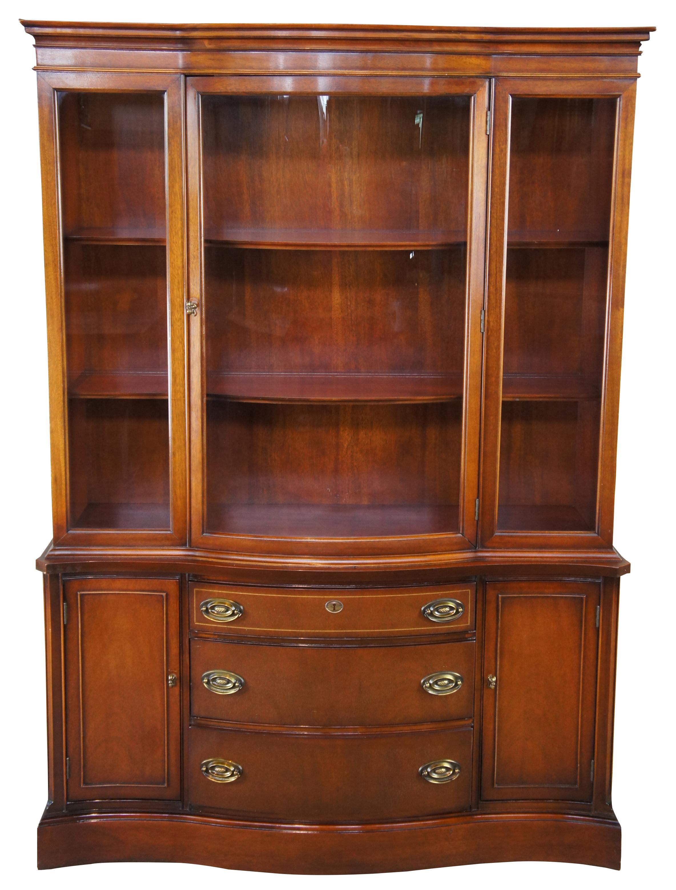 Vintage mid-century bow front china cabinet, made by Bassett Furniture in the 1950s as part of their Monticello collection. Featuring richly-hued mahogany and a curved glass door which matches the curved drawer fronts. This piece was constructed