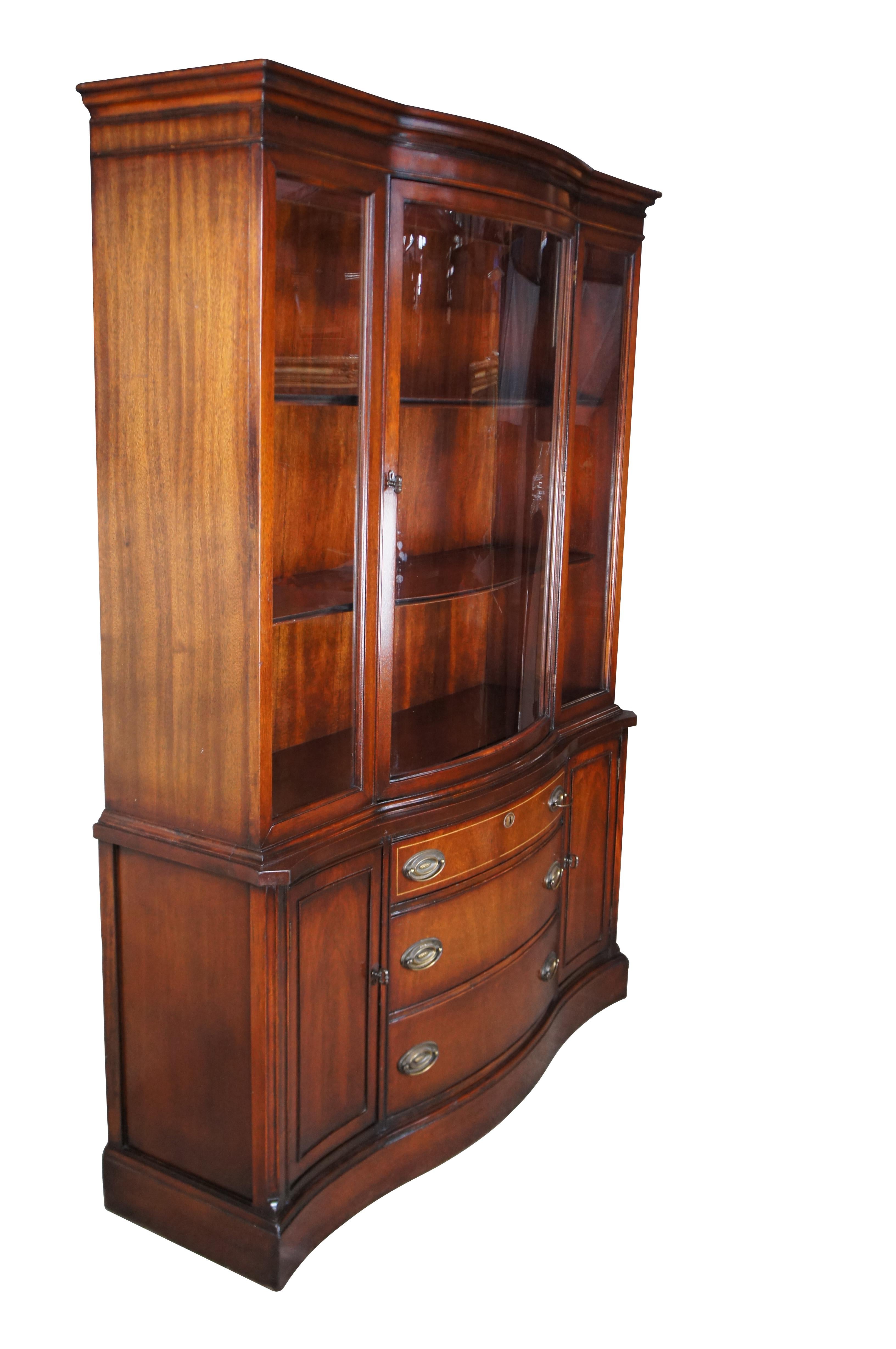 Vintage mid-century bow front china cabinet, made by Bassett Furniture in the 1950s as part of their Monticello collection. Featuring richly-hued mahogany and a curved glass door which matches the curved drawer fronts. This piece was constructed