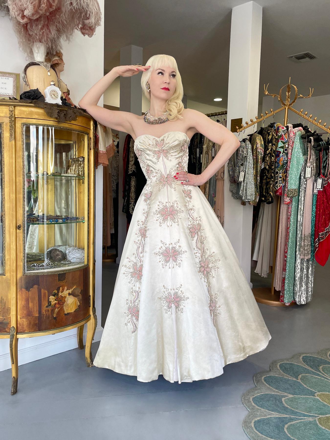 An absolutely breathtaking and incredibly rare Switzerland couture made for Lord & Taylor cream silk satin strapless full skirted ballgown dating back to the mid 1950's. As you can see, this custom commission was heavily influenced by Christian Dior
