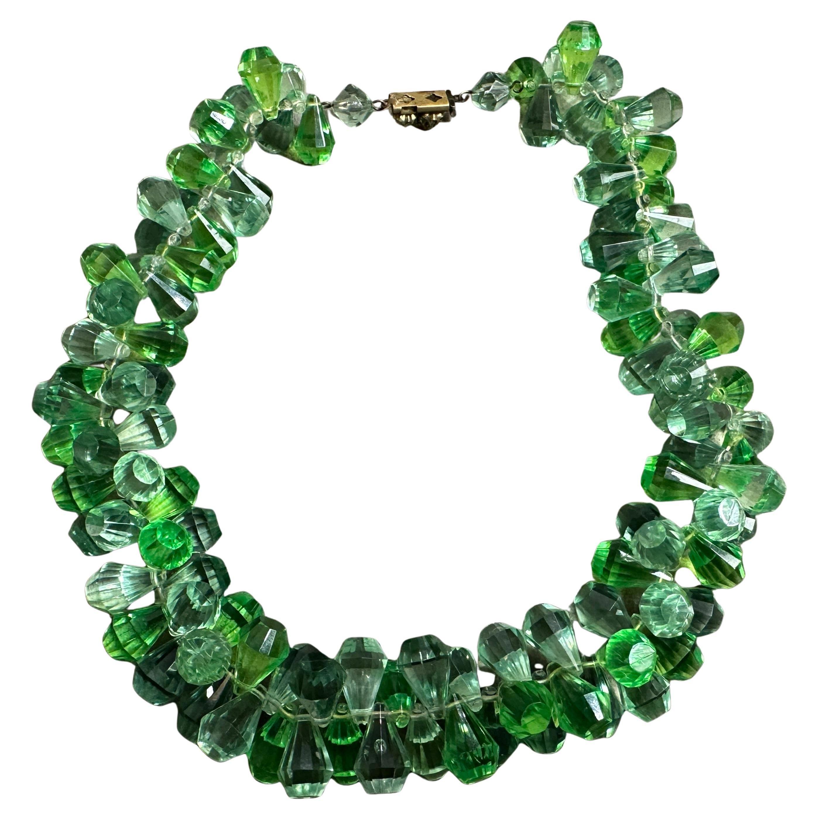 This is a vintage 1950s Italian beaded necklace made of green crystal. The necklace features faceted crystal beads in varying shades of green, creating a rich, multi-tonal effect. The beads are strung in a clustered, layered design that gives the