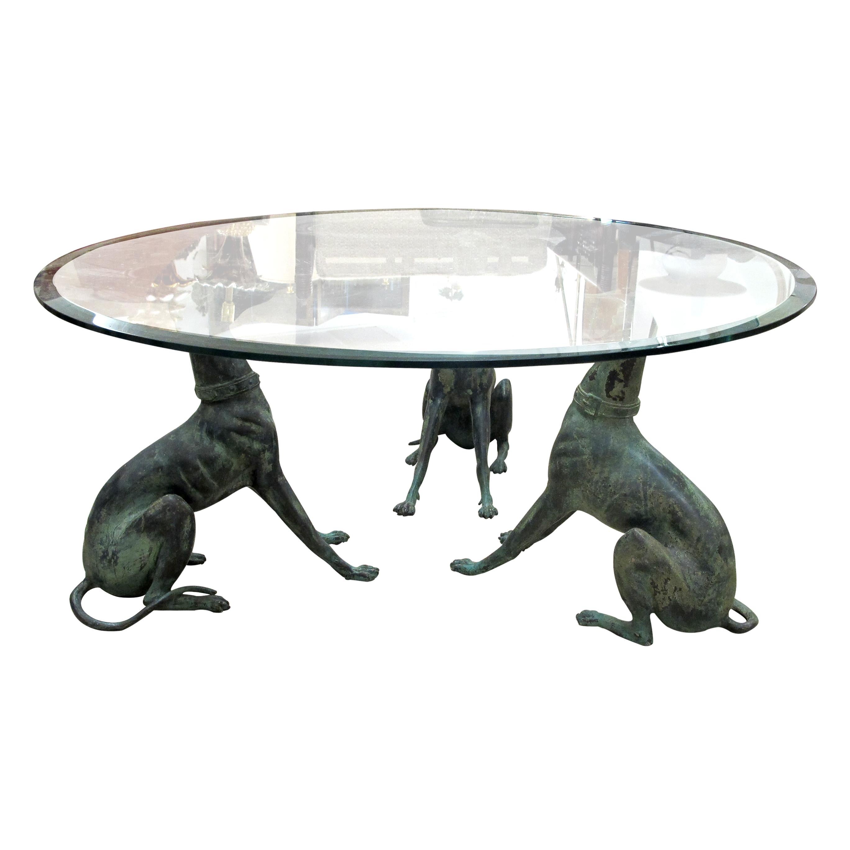 La mesa de centro belga de los años 50 es una notable fusión de elegancia y arte. Presenta una tapa redonda de cristal biselado sostenida por tres whippets de bronce finamente esculpidos con detalles realistas que le confieren gracia y un toque de