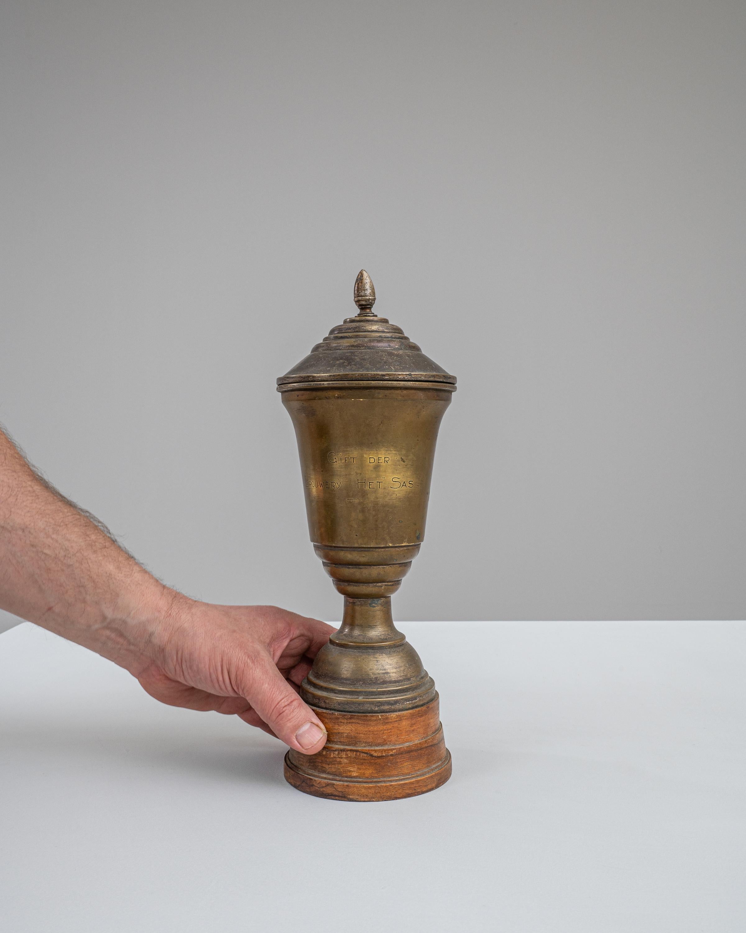 This 1950s Belgian Metal Goblet stands as a cherished relic from a bygone era, a token of recognition and achievement. Crafted from metal, it features a classic goblet design with a tapered cup that bears the marks and patina of time, giving it a