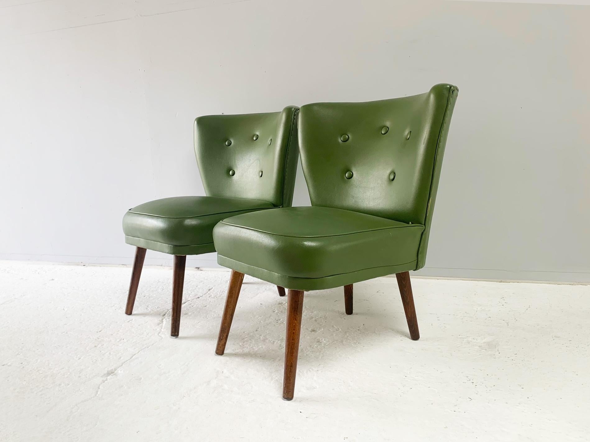 The price listed is for one chair. There are two chairs available.

Cocktail / occasional / bedroom chair, produced in Belgium in the late 1950’s. Upholstered in the original olive green leatherette (faux leather). Button detailing on back rest