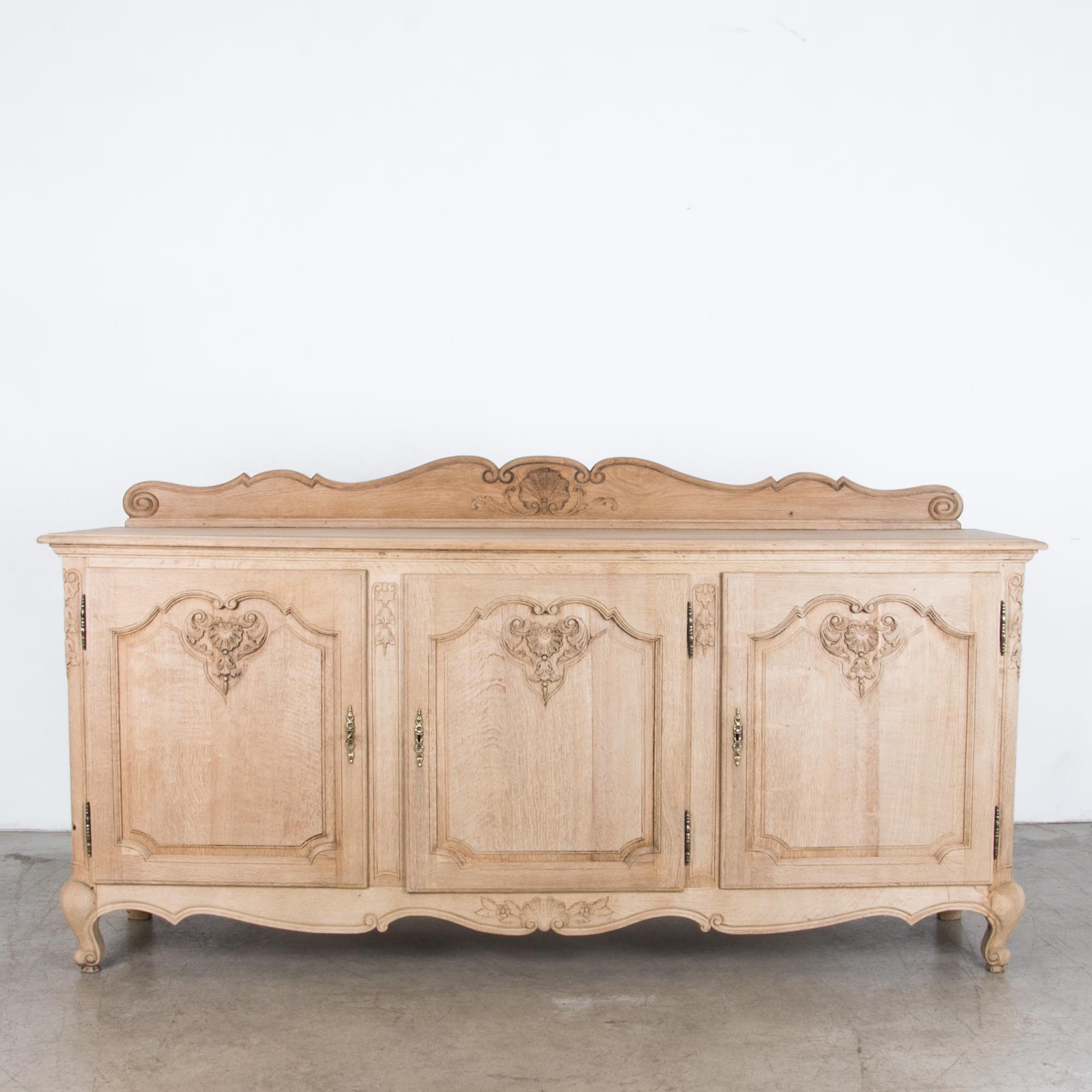 From circa 1950, a three-door and drawer cabinet in oak with drawer storage and carved wooden surround. A style inspired by earlier French provincial interior, influenced by the furniture and homes of Southern France, interpreted by the eyes of