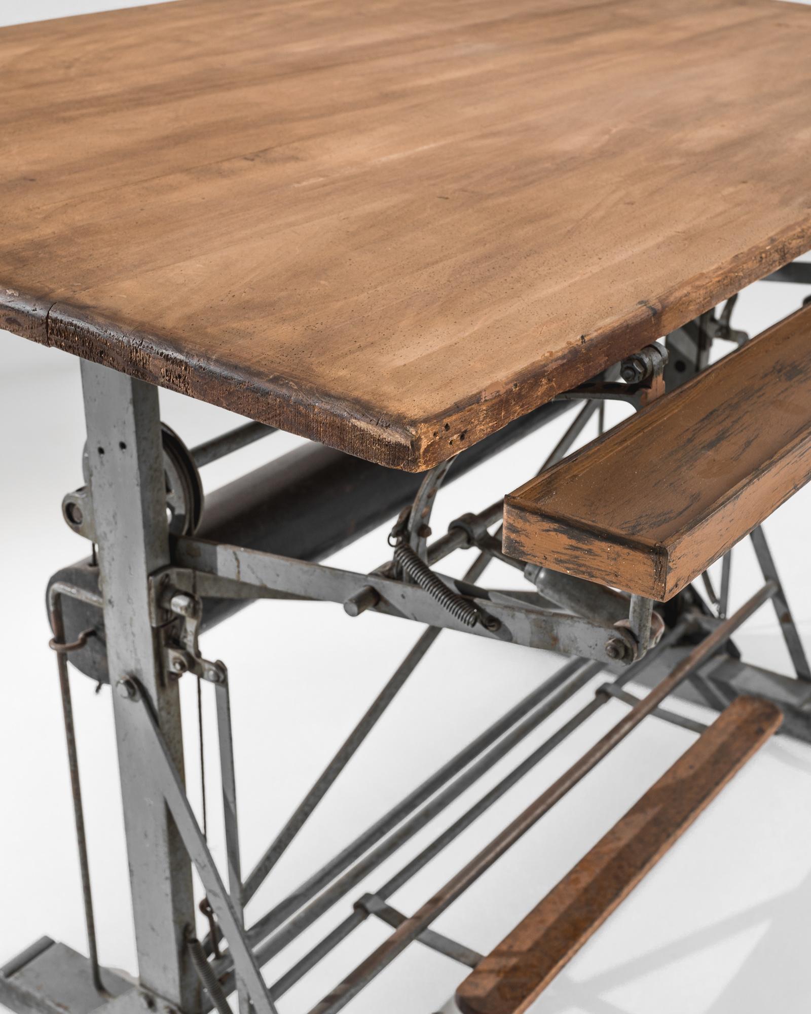 A Belgian metal drawing table with wooden top, dating from the 1950s. Both a work of engineering and art, this drawing table is sturdy and functional, while pleasantly eye-catching. Industrially crafted steel wheels, springs, and slides allow its