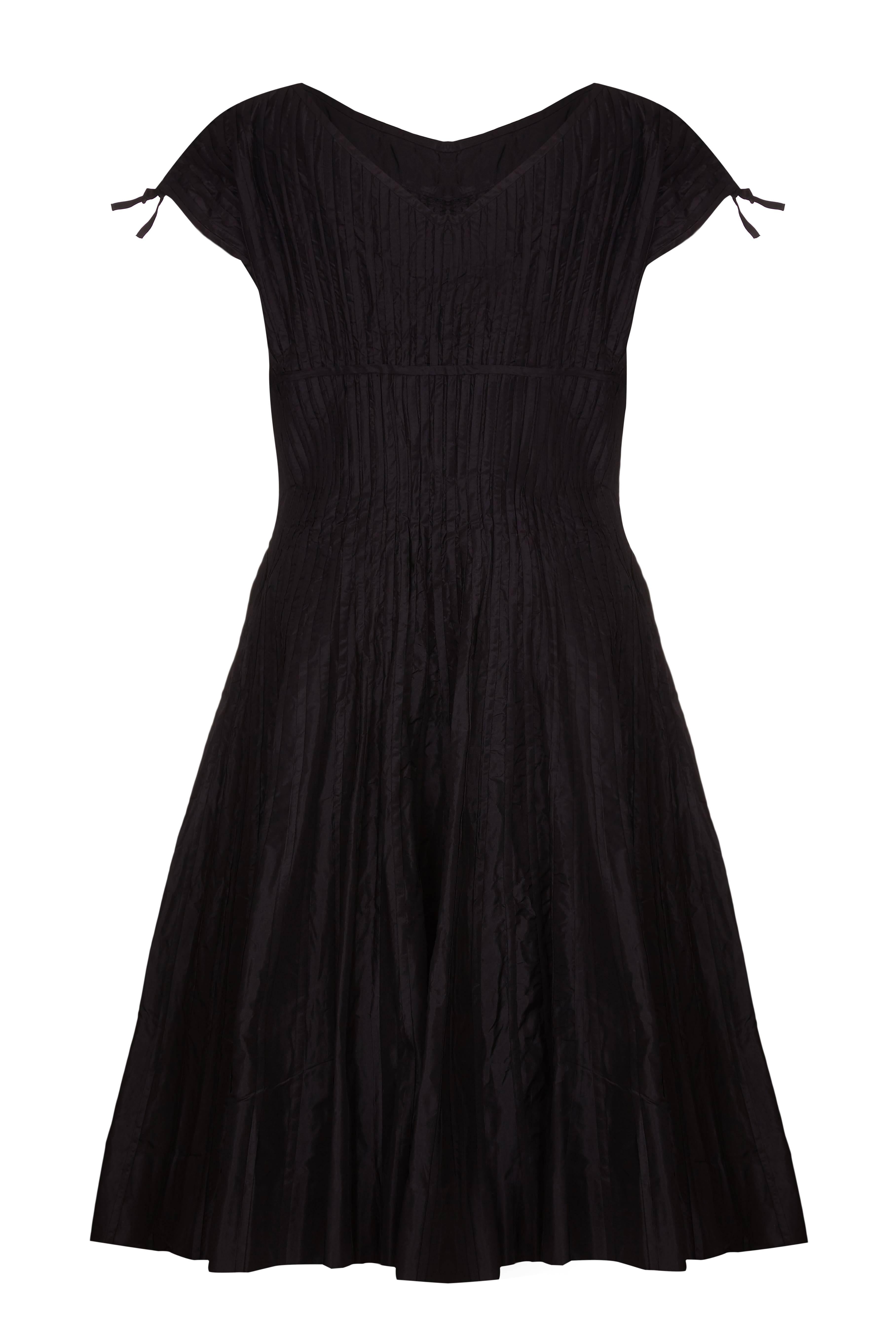 This beautiful early 1950s black silk dress is likely to be by Omar Kiam for designer Ben Reig, a brand renowned during this era for its simple, elegant lines and luxurious quality of fabrics. The silk fabric is textured with vertical applique