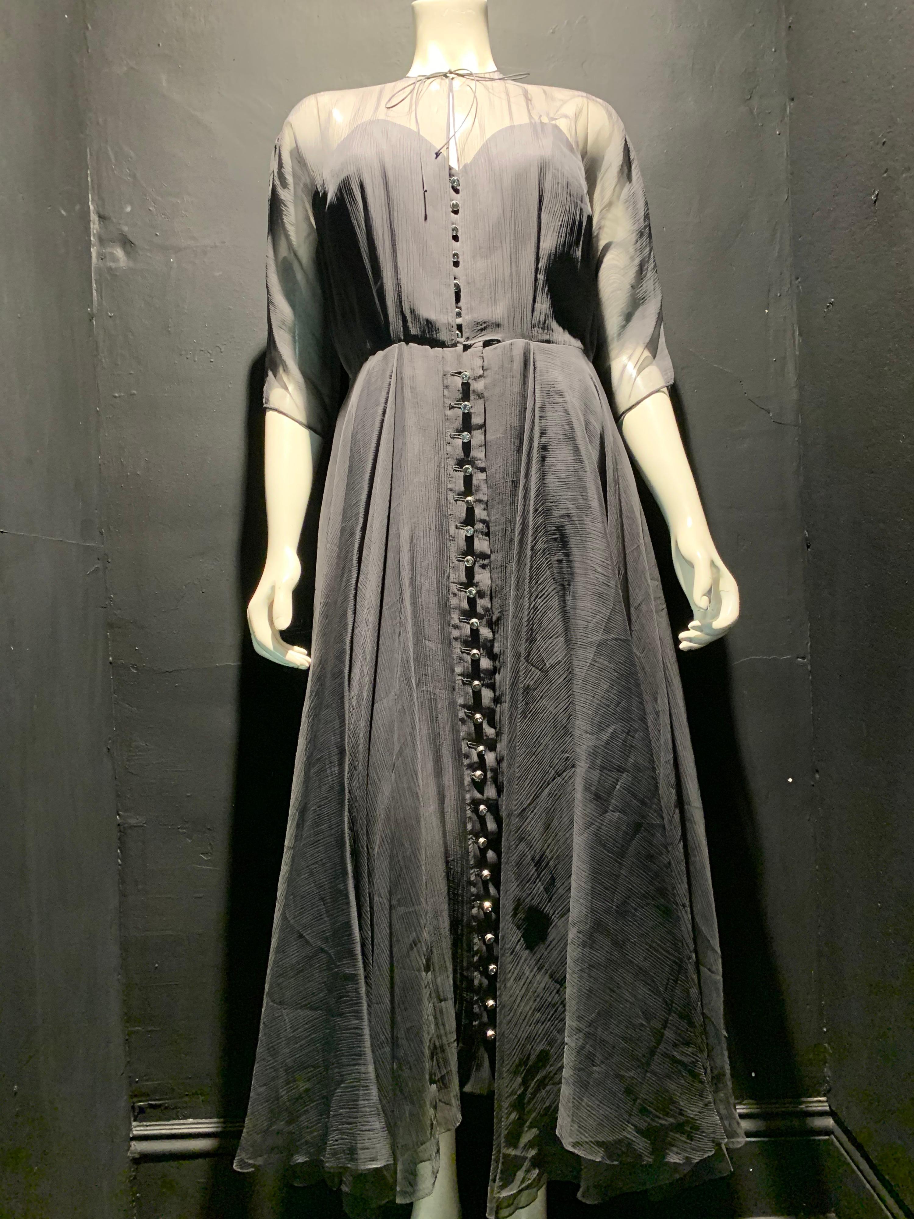 1950s Ben Reig smoke gray silk textured chiffon cocktail dress: Gorgeous rhinestone buttons run the length of the front pleated, 3/4 length dolman sleeve over-layer. Lined with crepe underlayer. Delicate silk tie at neck. This 