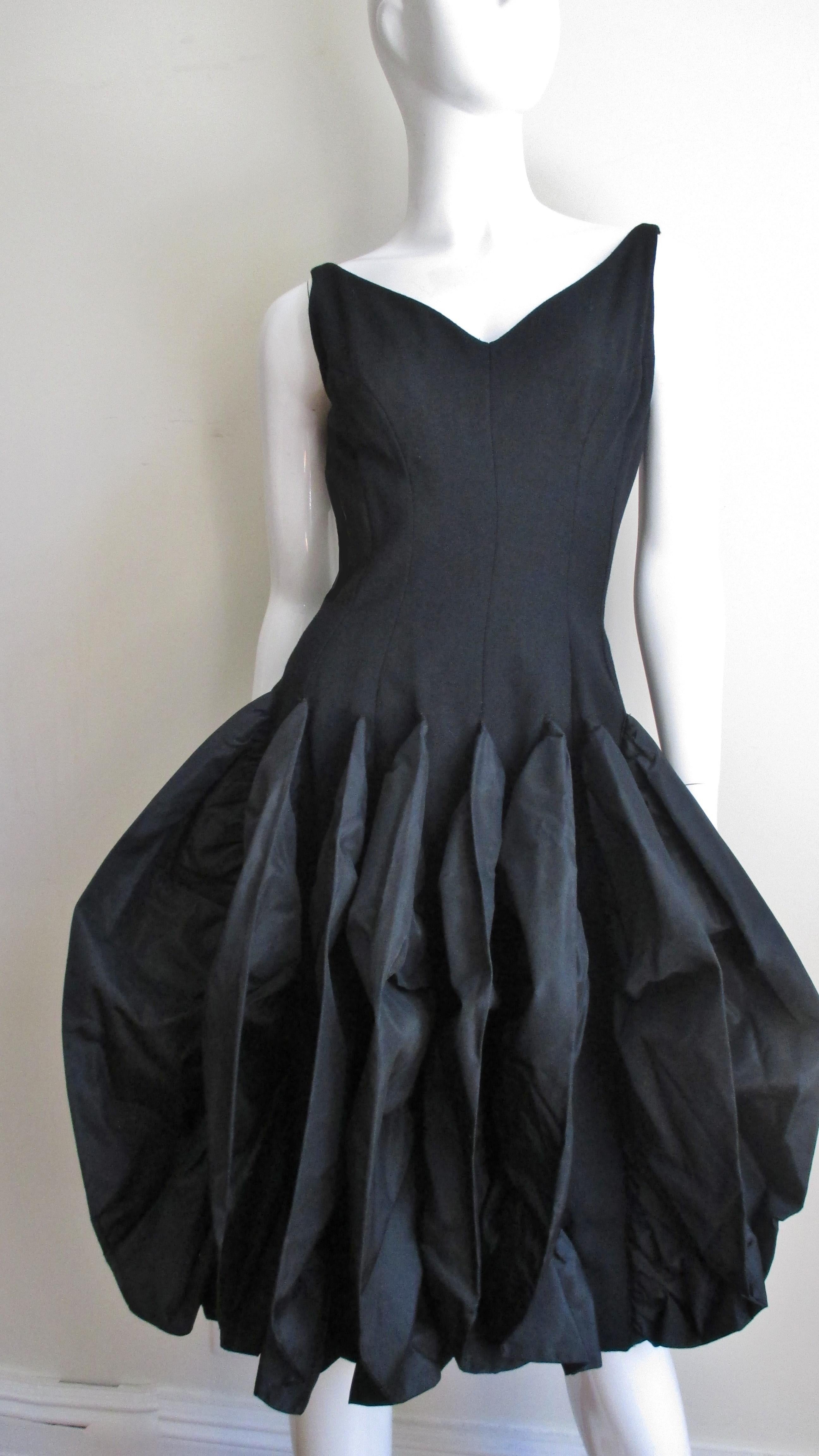 A fabulous dress from Betty Carol in light weight black wool and silk taffeta.  It has a V neckline front and back with fabulous princess seaming creating a fitted silhouette through to the lower waist.  It then flares into a rounded skirt covered