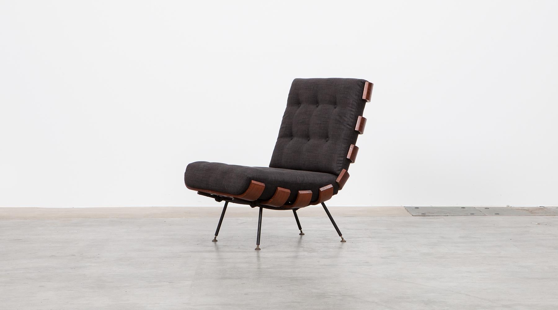 Wonderful Brazilian lounge chair designed by Martin Eisler and Carlo Hauner. The chair has been produced in teak and plywood slats bent elegant to the ends and stands on a black lacquered metal frame with brass feet. The cushions are recently newly