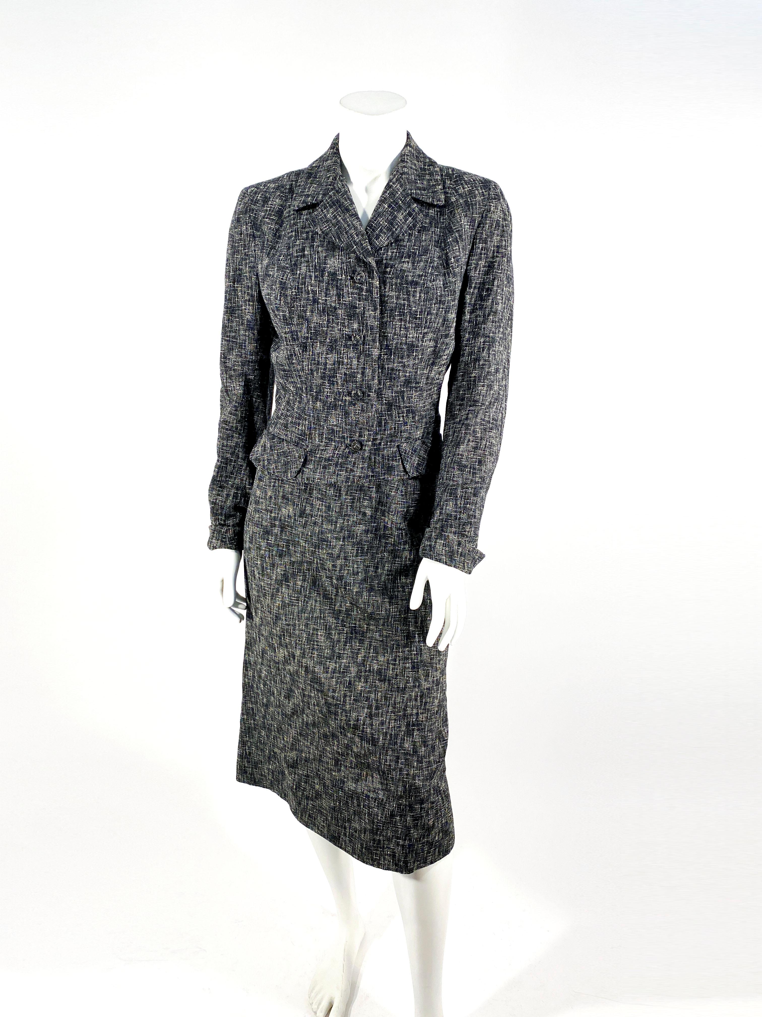Costume en laine tissée mouchetée noire et grise des années 1950. La veste a une allure ajustée et des boutons recouverts à la main. Le tissu est une laine d'été et les épaules sont légèrement paddées.