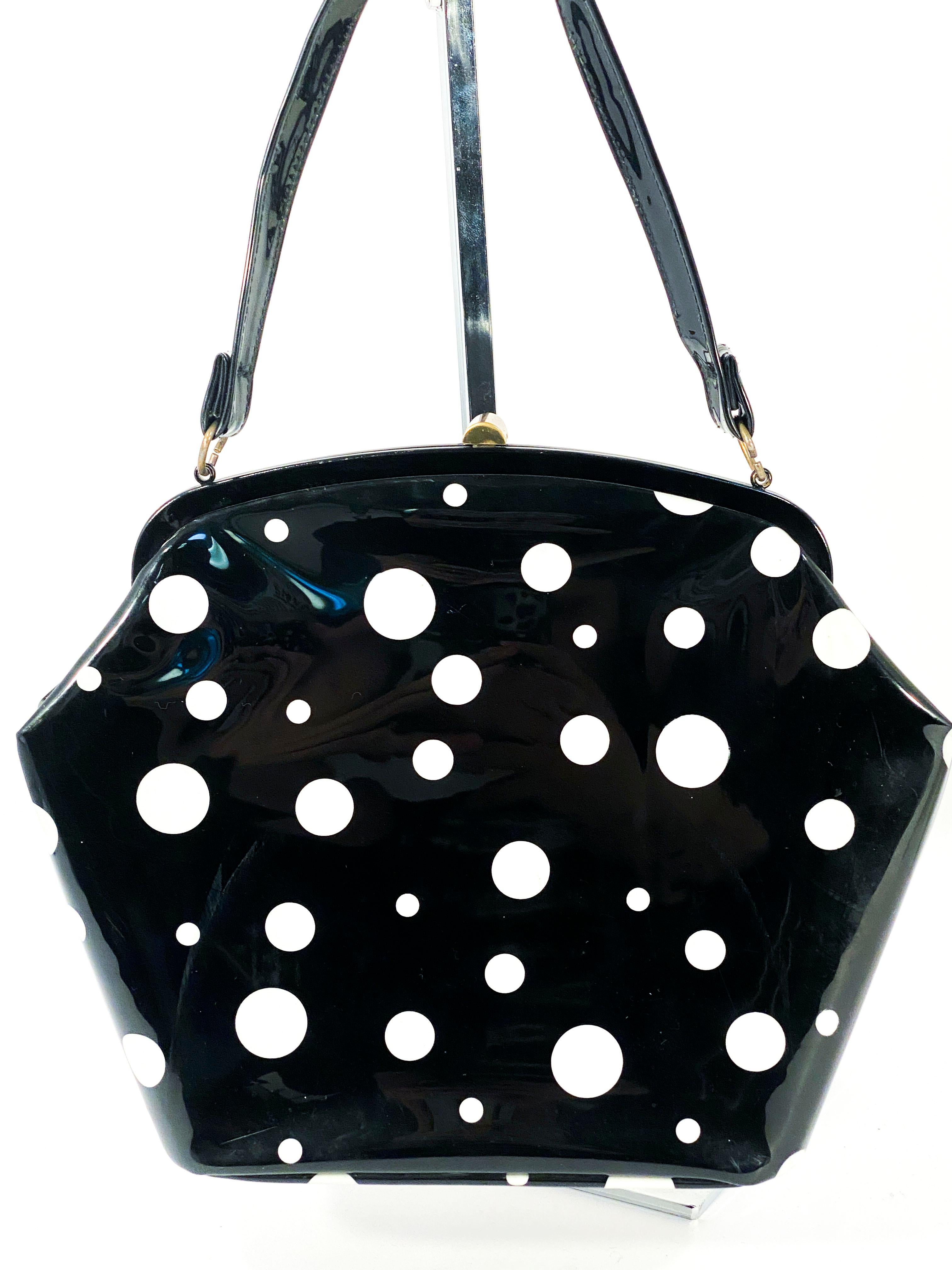 1950s Black and white polka dot leatherette purse with brass hardware and black lining with two interior pockets. The belt is original however is in useable shape but the interior is rough. We priced this item for the purse alone but we will include