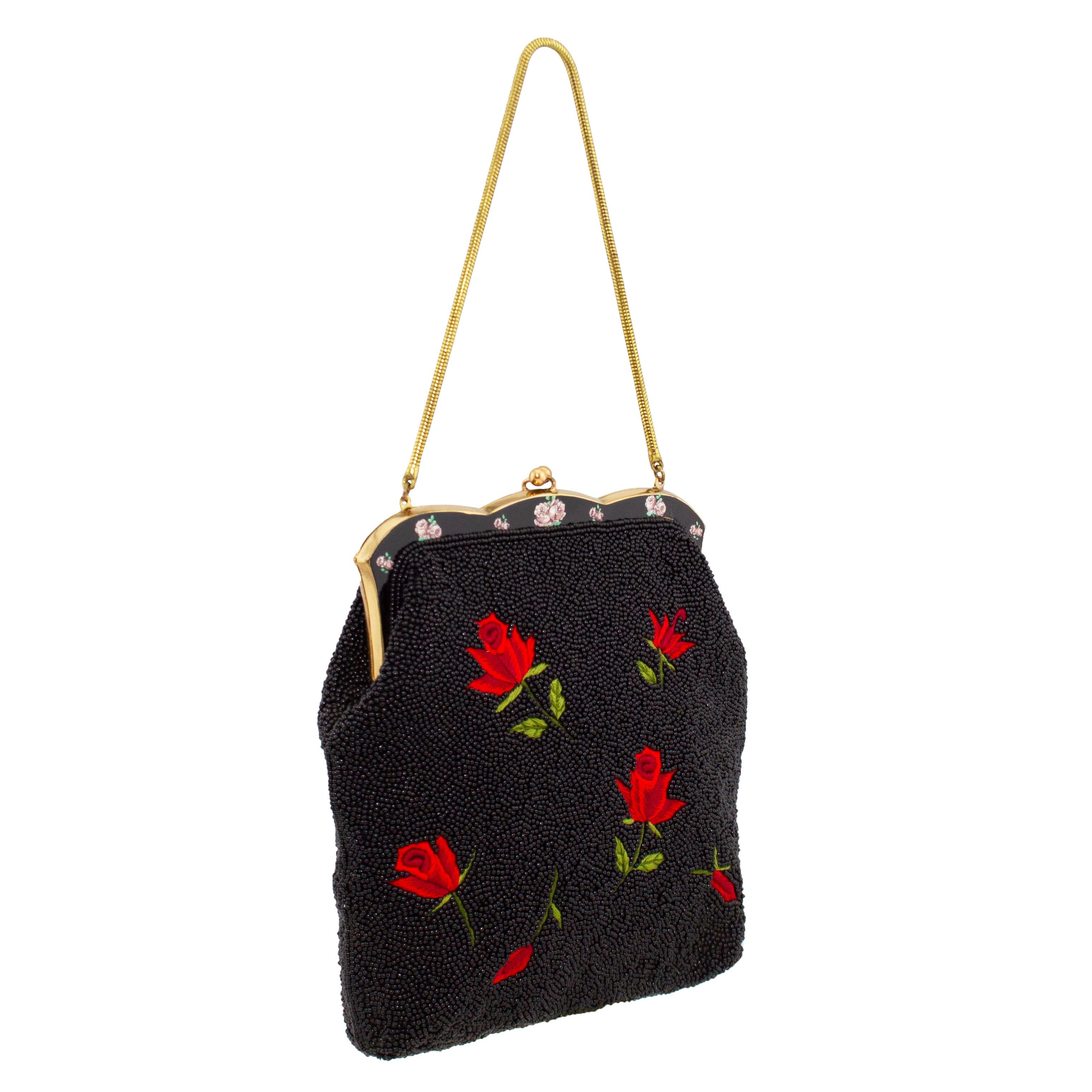 The most beautiful evening bag from the 1950s. This piece is completely encrusted in tiny jet black seed beads that are vividly contrasted by embroidered red and green roses. The frame of the bag is gold tone and black metal with small pink rose