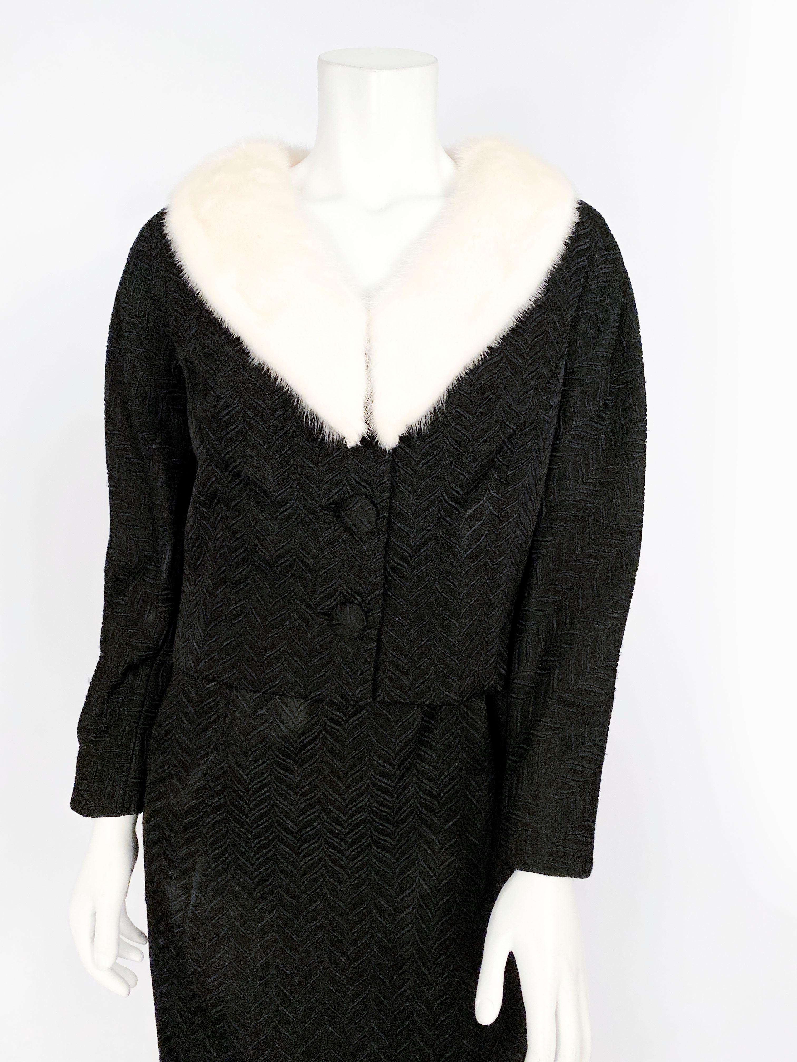 1950s dress with matching jacket made of a black herringbone patterned jacquard in contrast to the jackets' cream mink collar. The jacket is cropped with full length sleeves and a silk lining. 