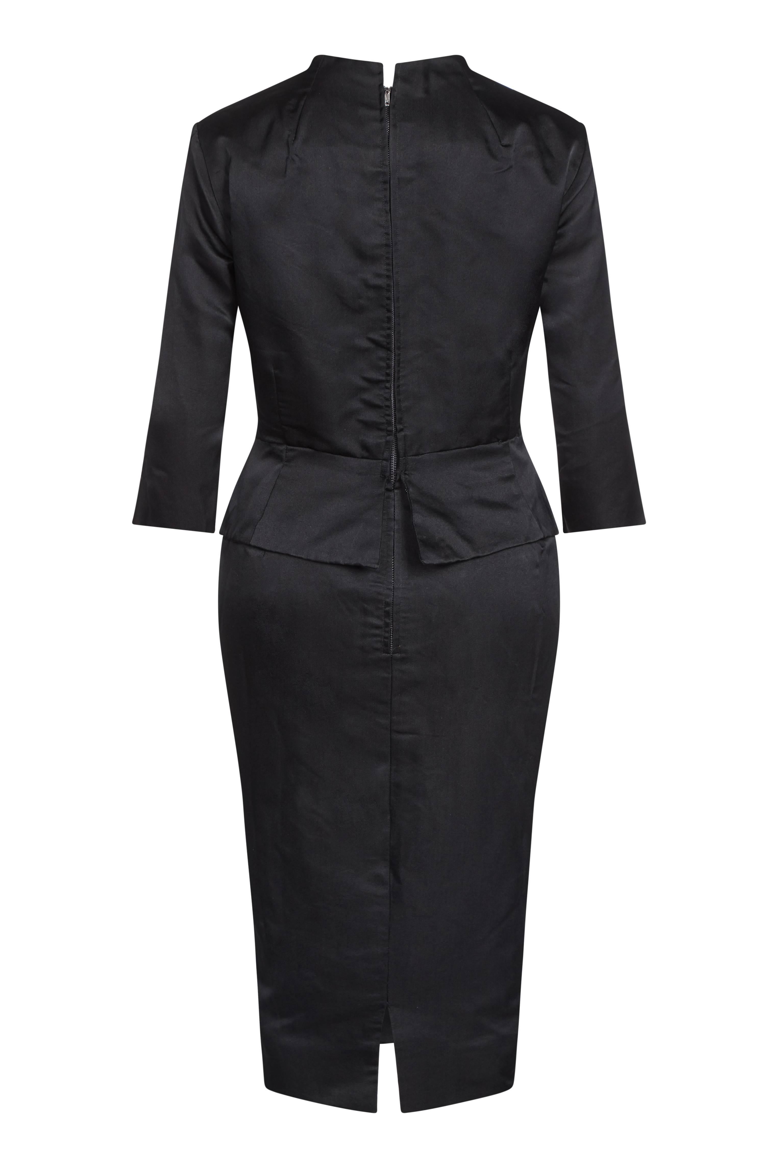 This stylish 1950s black silk evening dress is a stunning combination of design features, achieving a deeply glamorous yet formal evening look. The mid-length sleeves and peplum detail in addition to skilled tailoring at the waist and hip creates a