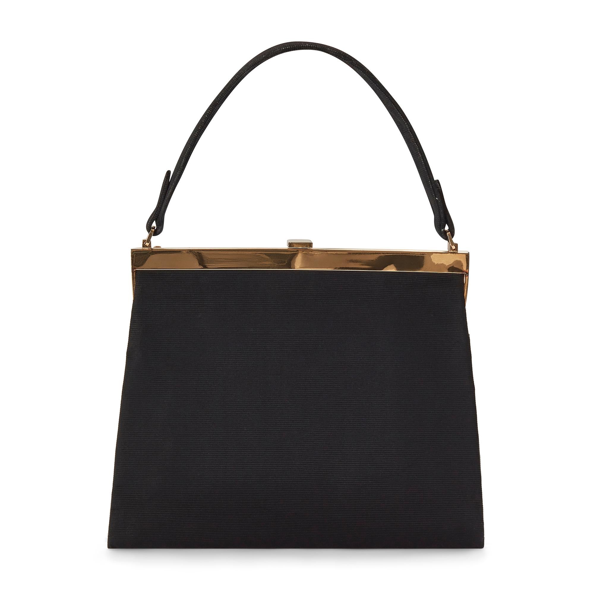 This elegant bag was made for Fortnum & Mason in the 1950s. Crafted from black silk grosgrain, it has a slim profile and an envelope design, complete with a bow. The short handle is made from coordinating grosgrain silk. The gold-toned hardware is
